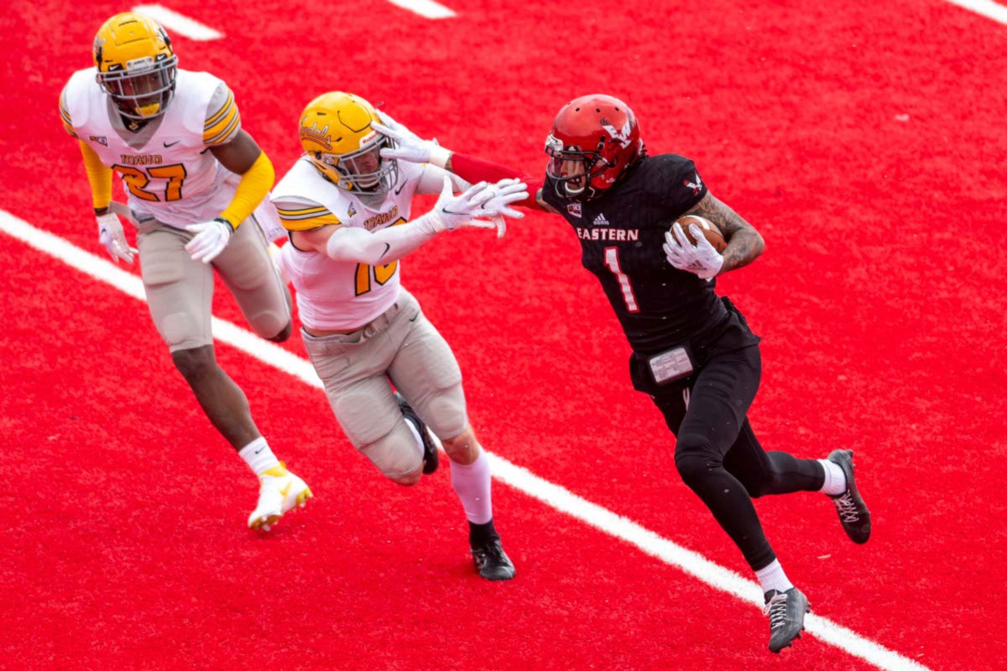 Eastern Washington receiver Talolo Limu-Jones, right, stiff arms Idaho defensive back Jaxon Woodward, center, during the first quarter of Saturday’s Big Sky Conference game at Roos Field in Cheney, Wash.