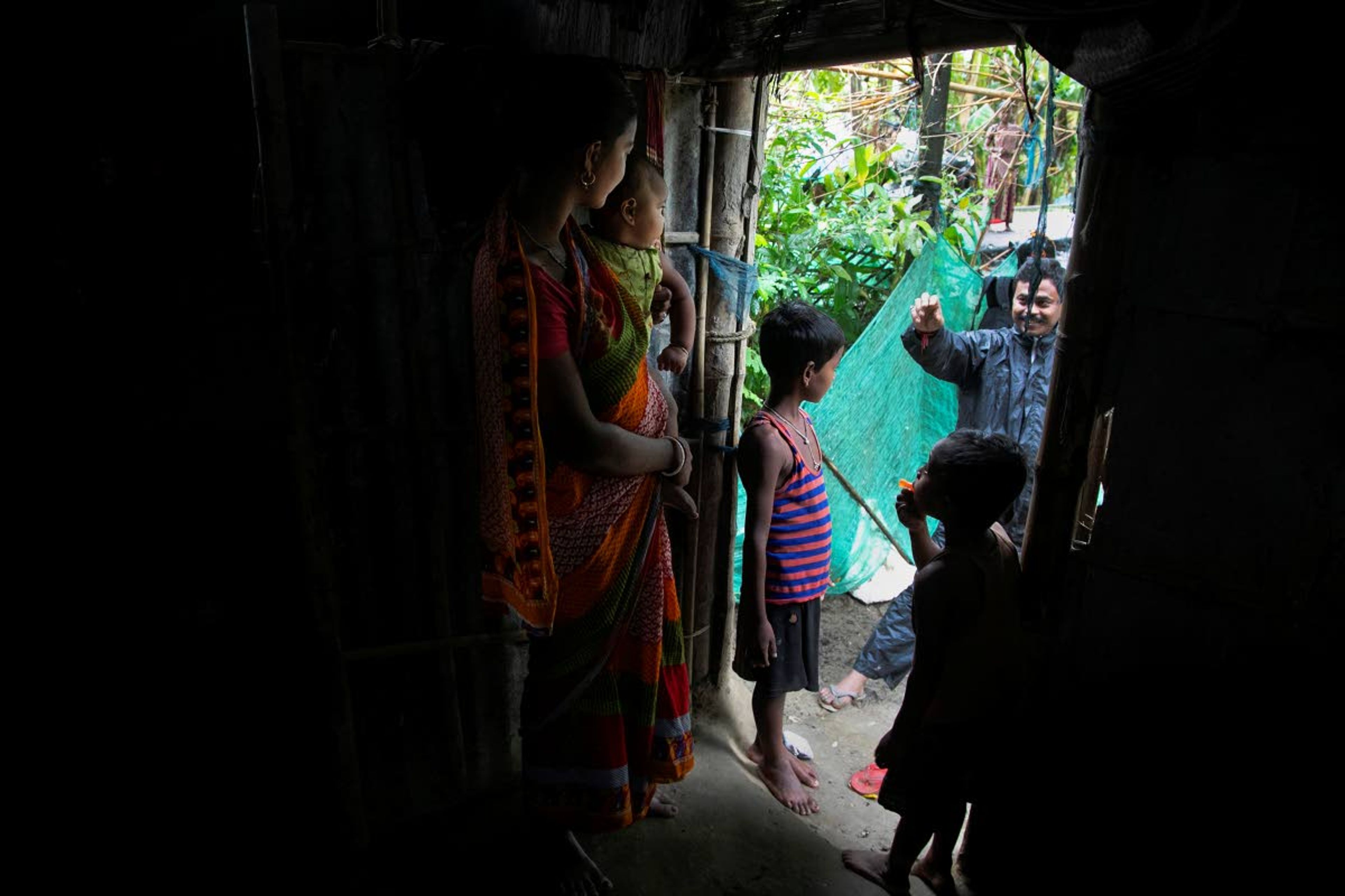 Ramananda Sarkar, 43, talks to his children from a distance in Theng Bhanga village, in Morigaon district, India, Tuesday, Sept. 22, 2020. Sarkar, who was deep in debt and desperate for money, took the job of lighting funeral pyres after failing to pay back a loan he'd taken to start selling sugarcane juice on a wooden cart. Dealing with corpses is a stigma that's only been made worse by the coronavirus, which has killed more than 100,000 people in India out of 6.4 million reported infections. After a month and a half of not seeing his wife and three sons, Sarkar snuck into his village in the middle of a recent rainy night and was able to spend 15 minutes with them and leave them some money. (AP Photo/Anupam Nath)