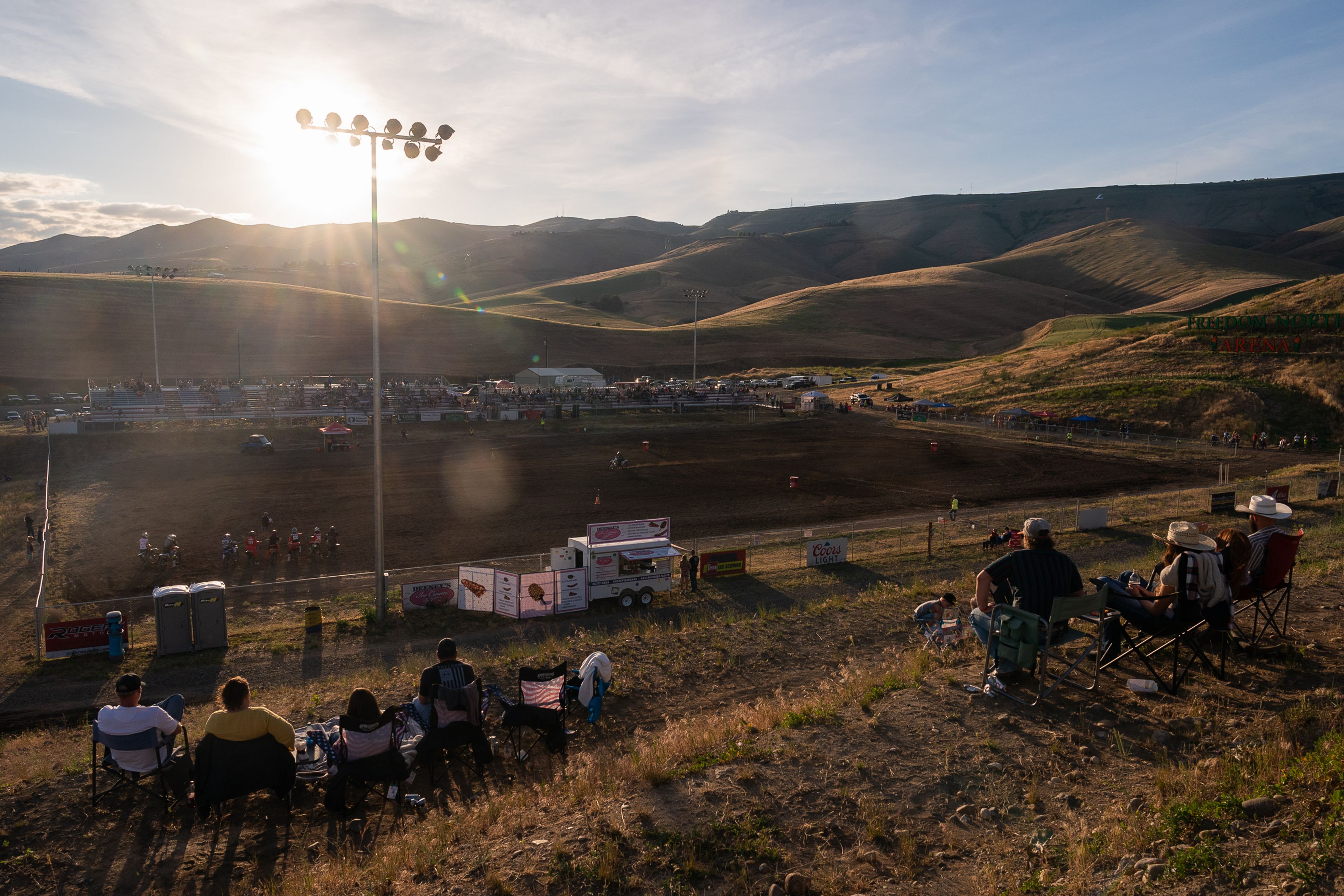 Fans watch as motorcycle riders race around the course during the Horsepower vs Horse Power event Saturday evening at ECMX Park in Lewiston.