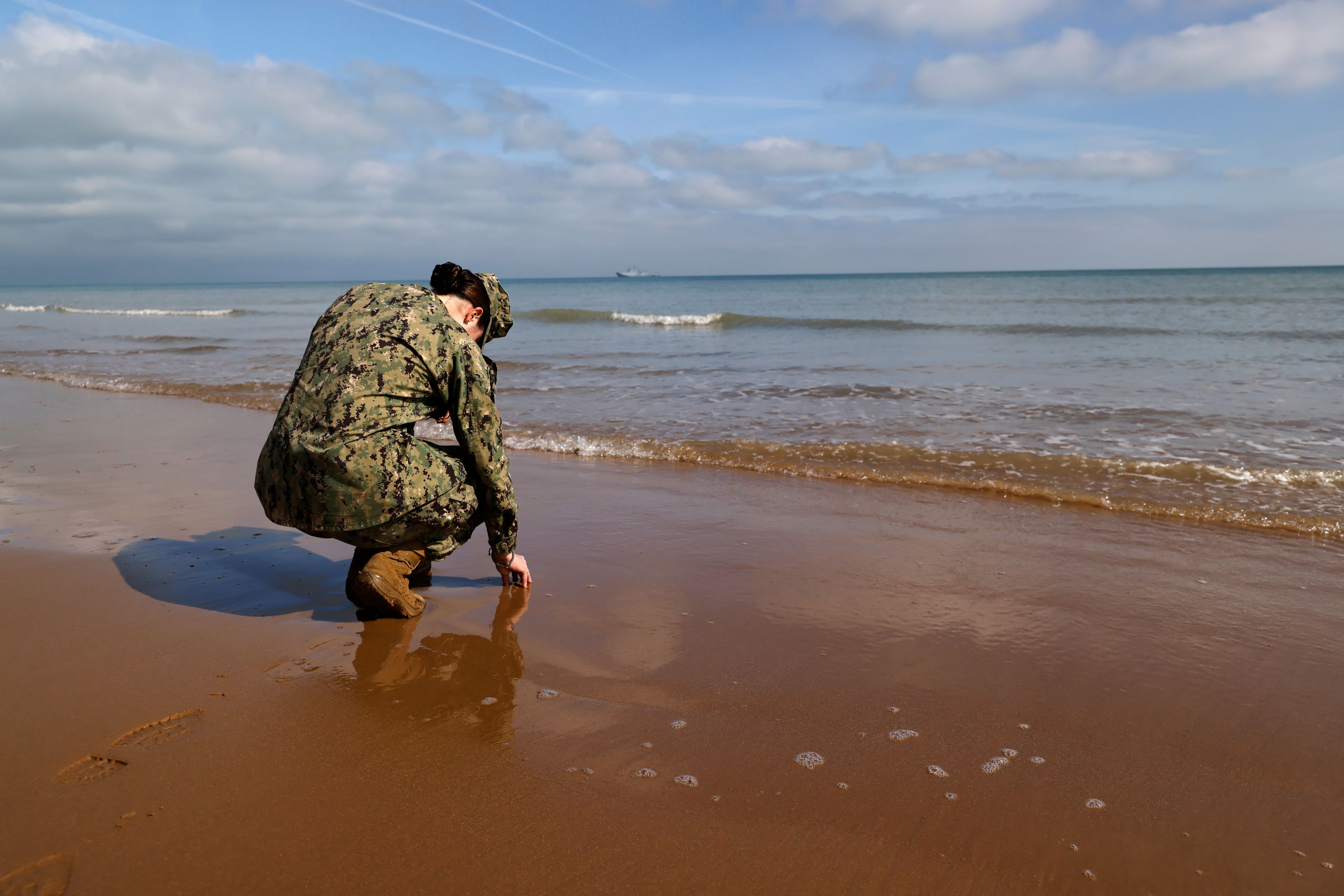 An American soldier touches the sand on Omaha Beach, Tuesday, June 4, 2024 in Normandy. World War II veterans from across the United States as well as Britain and Canada are in Normandy this week to mark 80 years since the D-Day landings that helped lead to Hitler's defeat. (AP Photo/Jeremias Gonzalez)