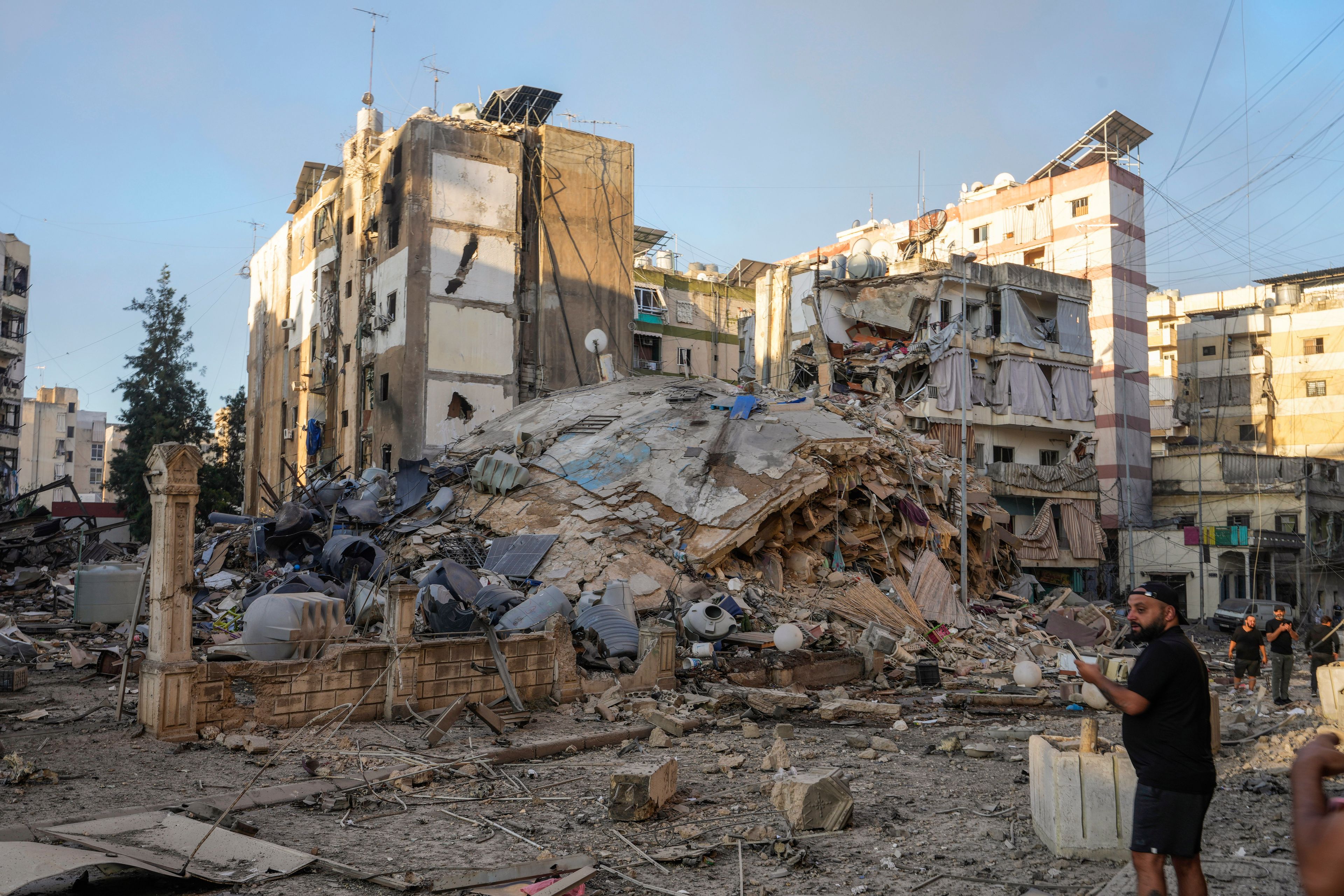 A man documents the damaged buildings at the site of an Israeli airstrike in Dahiyeh, Beirut, Lebanon, Friday, Oct. 4, 2024. (AP Photo/Hassan Ammar)