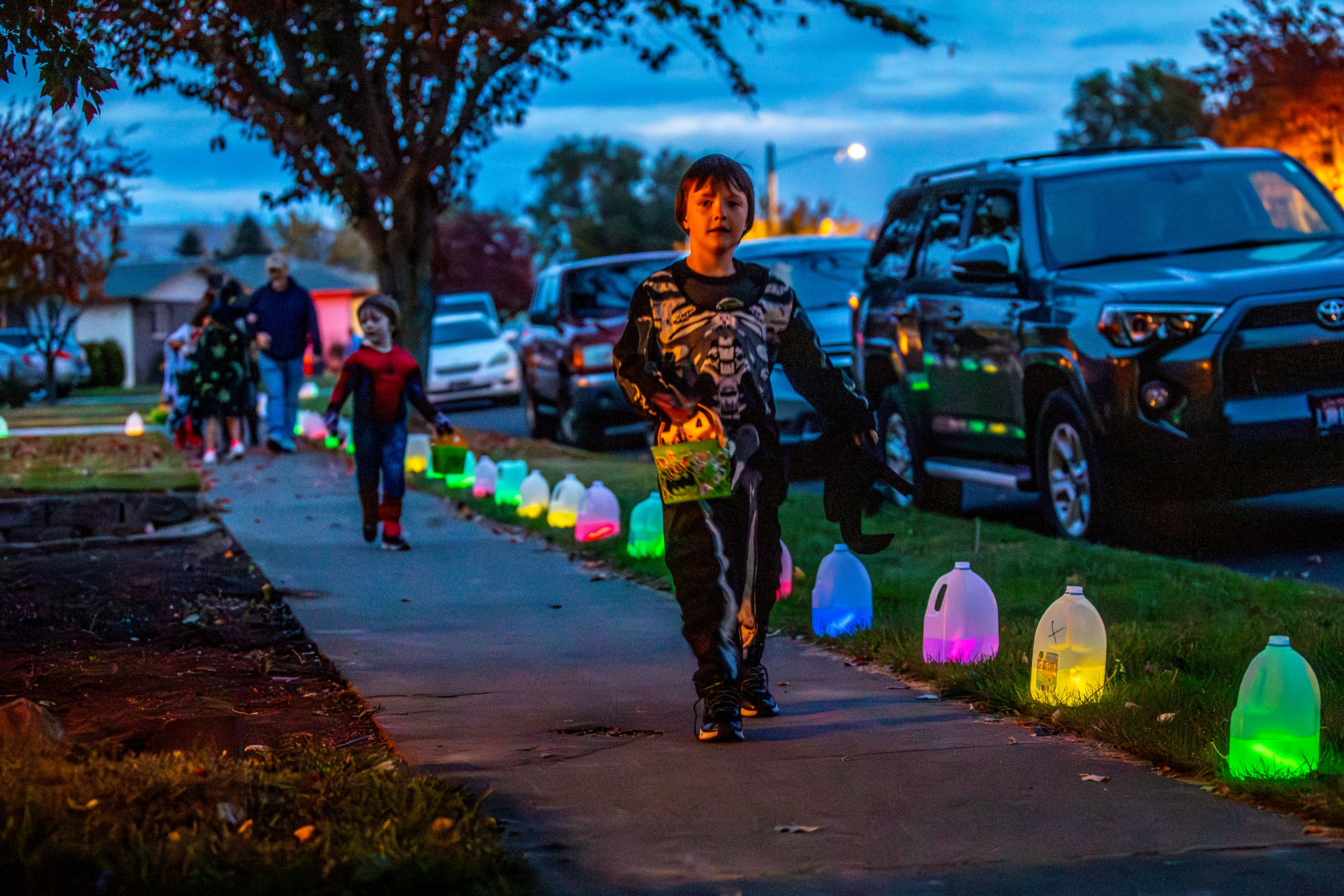 David Wauer, 6, dressed as Ghostface, runs along a sidewalk lined with gallon jugs of water with glow sticks in them Thursday in the Sunset Drive neighborhood in Lewiston.