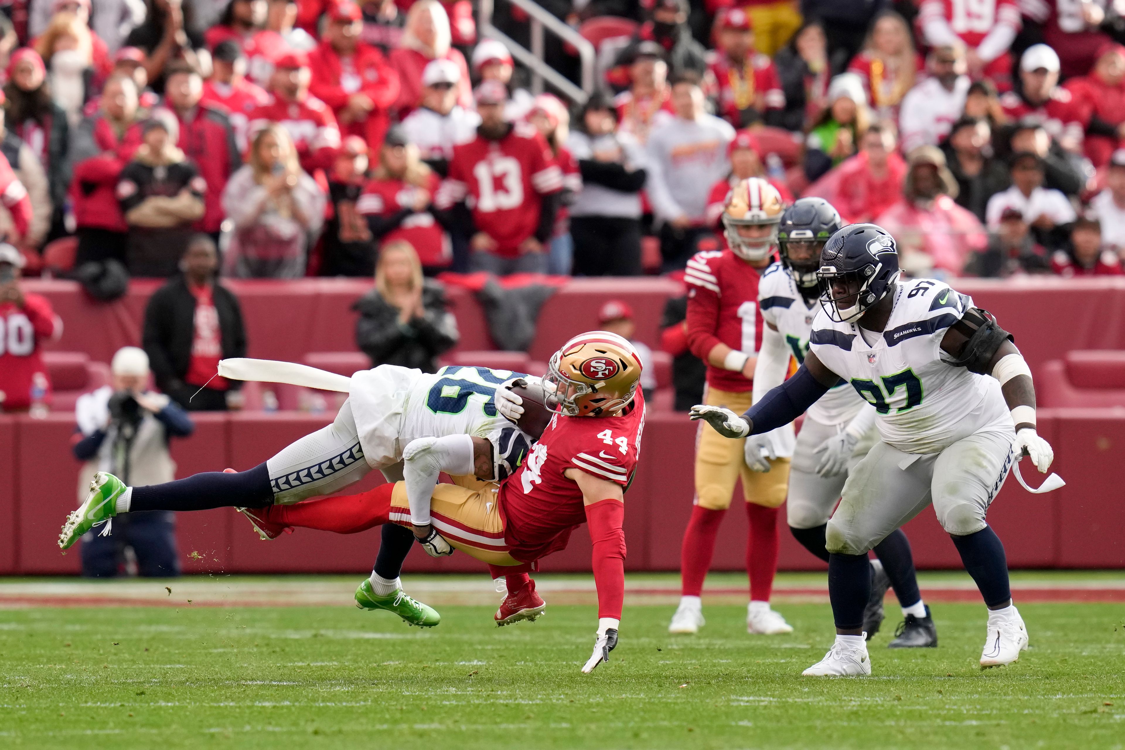 San Francisco 49ers fullback Kyle Juszczyk (44) is tackled by Seattle Seahawks safety Ryan Neal (26) as defensive tackle Poona Ford (97) looks on during the second half of an NFL wild card playoff football game in Santa Clara, Calif., Saturday, Jan. 14, 2023. (AP Photo/Godofredo A. Vásquez)