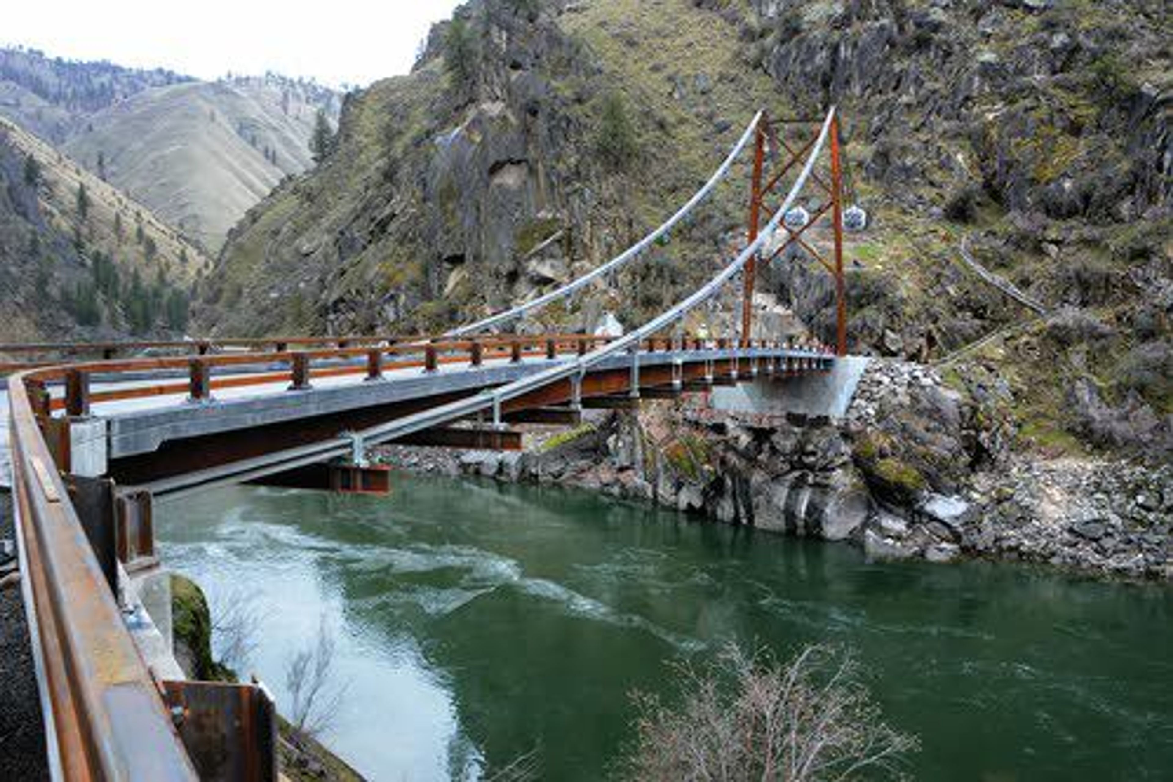 ABOVE: The new suspension-cable Manning Crevice Bridge that crosses the pristine Salmon River above Riggins is nearly complete.LEFT: Tight turns onto and off the old bridge were reduced a little with the new structure. BELOW: Six cables, each three inches thick, run the length of the bridge on both sides and are buried deep into the ground.