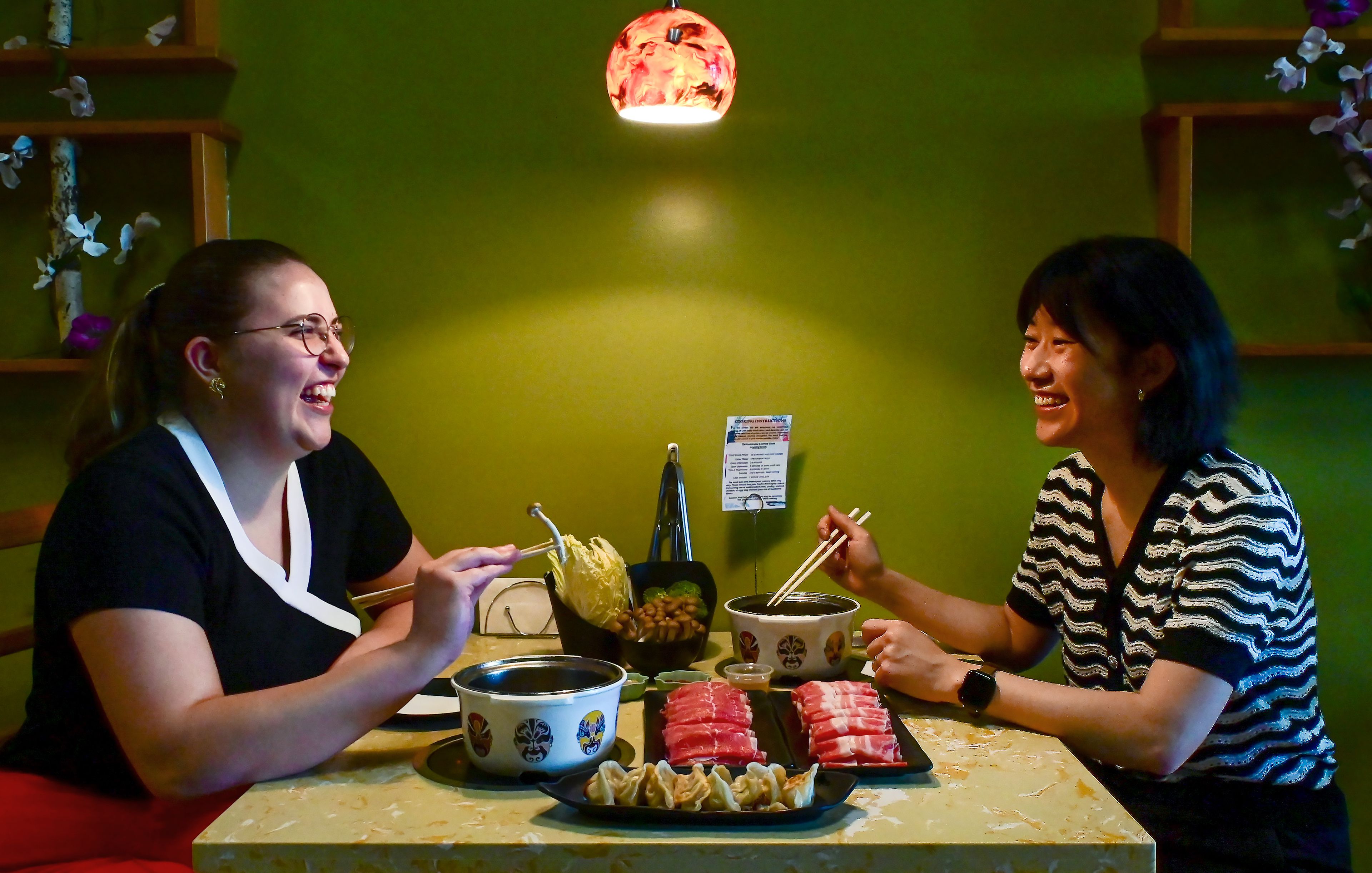 Everhot Hot Pot manager Meredith Sleight, left, and owner Jessica Liu laugh over a table of hot pot selections at the restaurant on Wednesday.