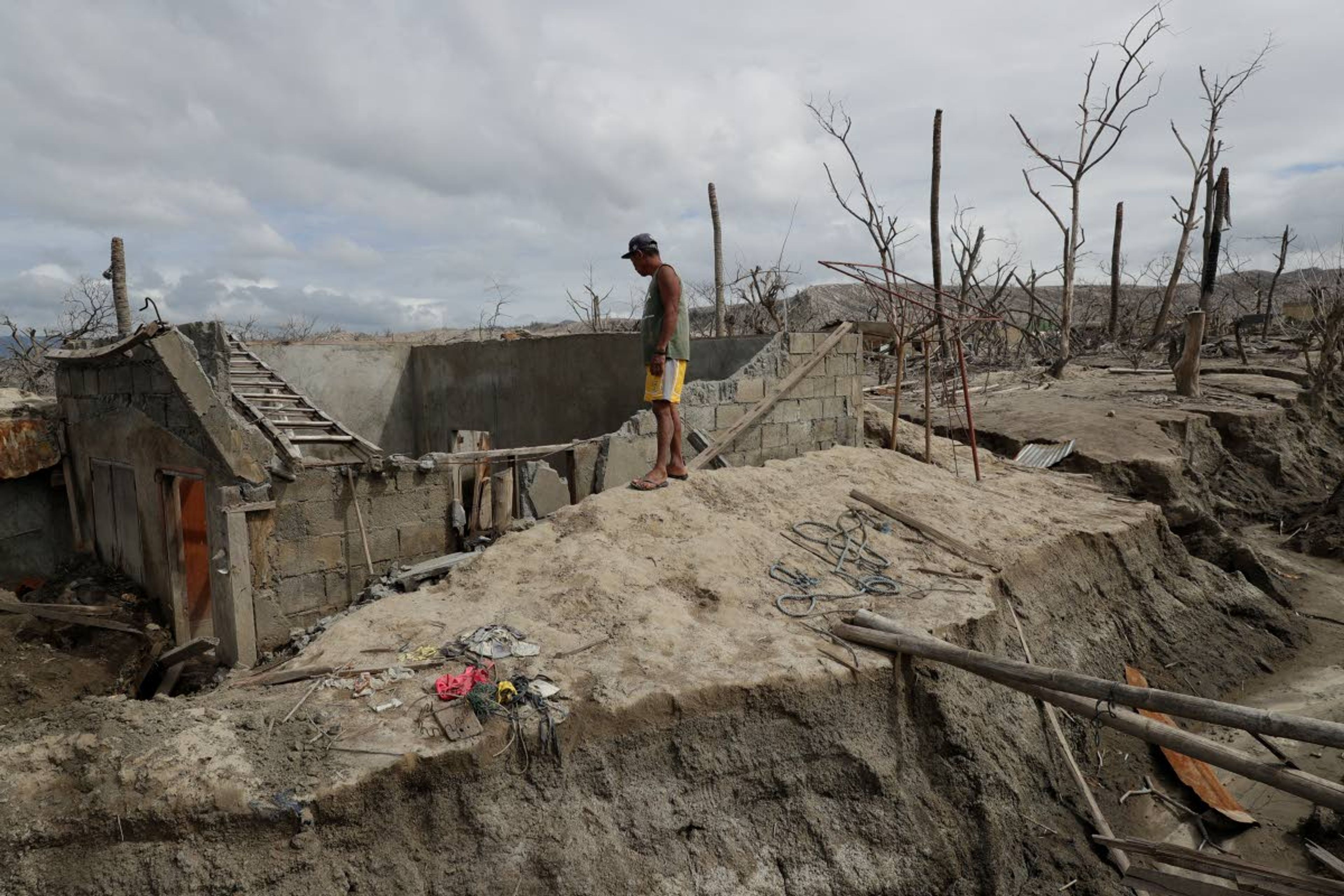 Fisherman Rogelito Cacao looks at the remains of his house at the Taal volcano.