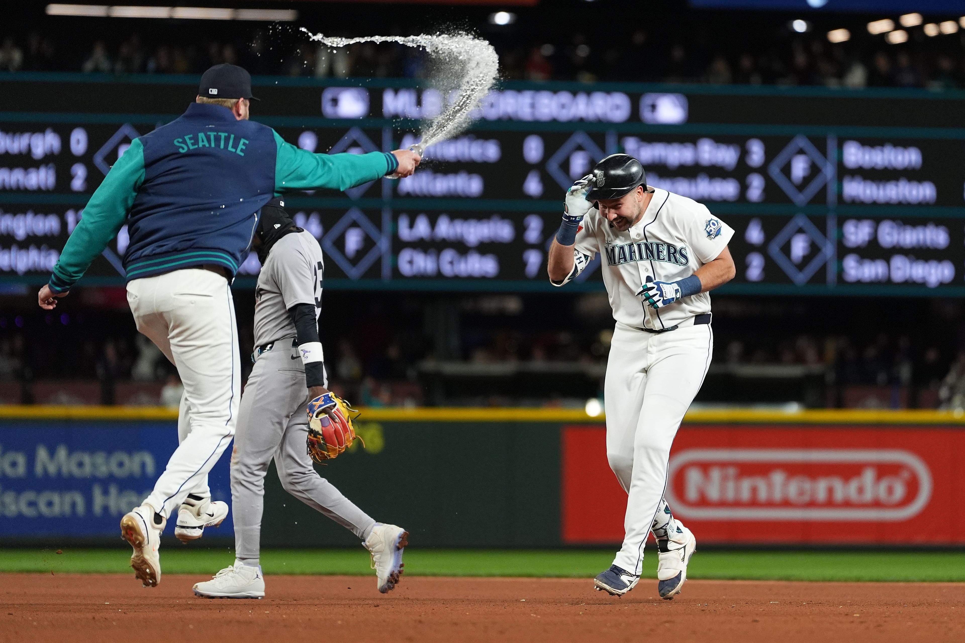 The Mariners’ Luke Raley, left, throws water on Cal Raleigh to celebrate Raleigh’s game-winning single as Yankees second baseman Jazz Chisholm Jr. walks away after a baseball game Monday in Seattle.