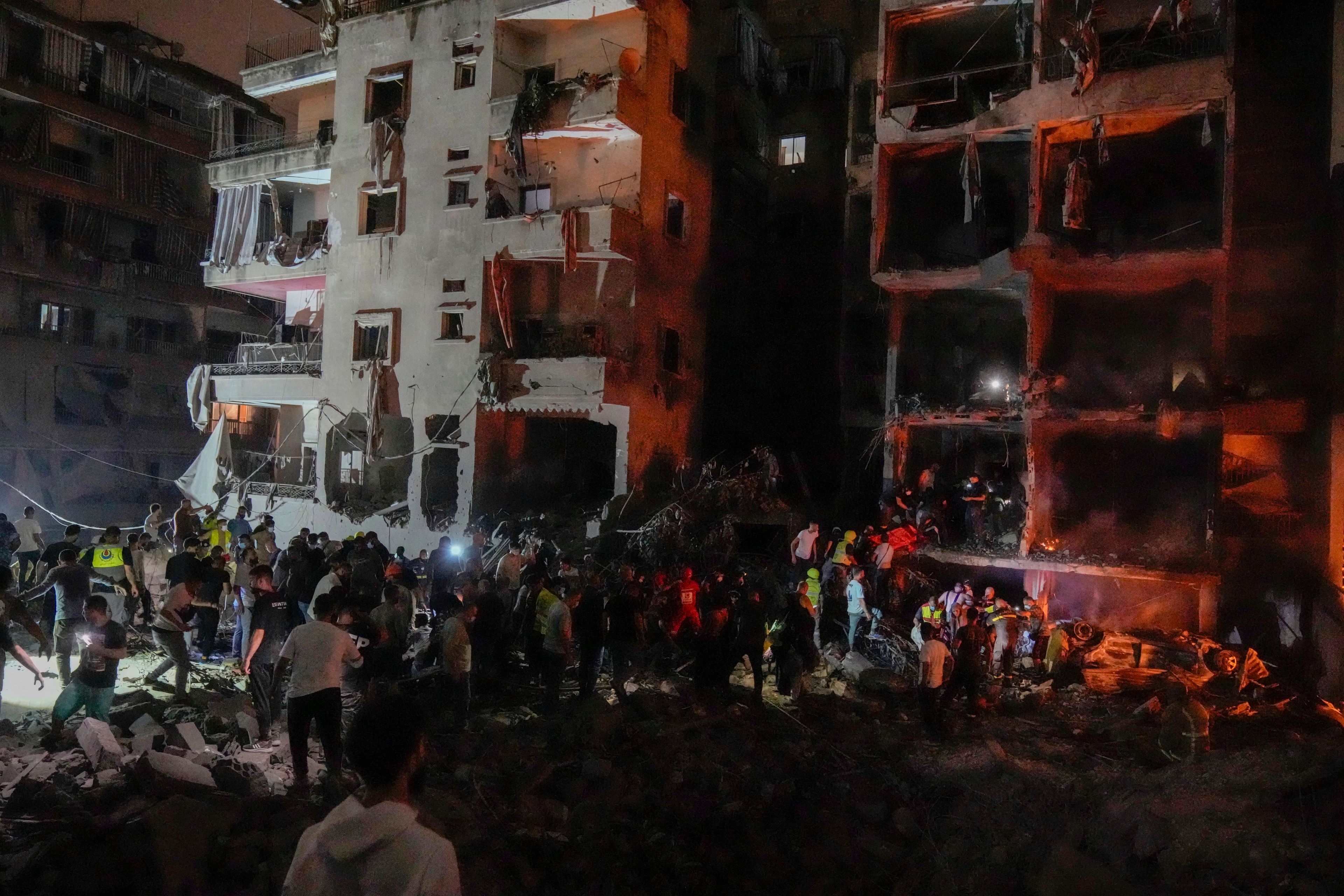 People gather in front of destroyed buildings hit by an Israeli airstrike in central Beirut, Lebanon, Thursday, Oct. 10, 2024. (AP Photo/Bilal Hussein)