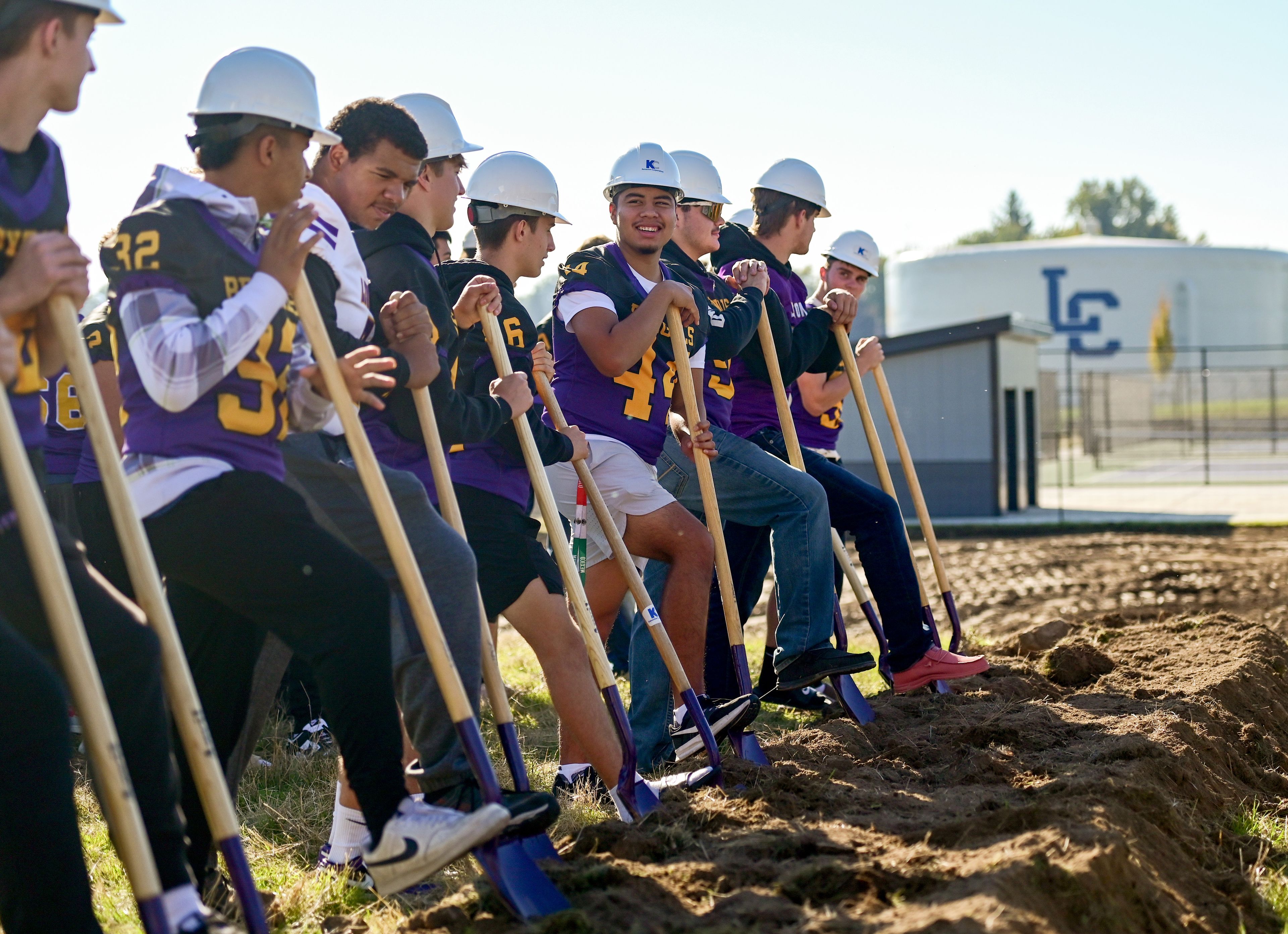 Lewiston High School football players put on construction hats and take hold of shovels for a photo at the groundbreaking event for the beginning of Phase II construction on LHS’s athletic venues on Saturday.