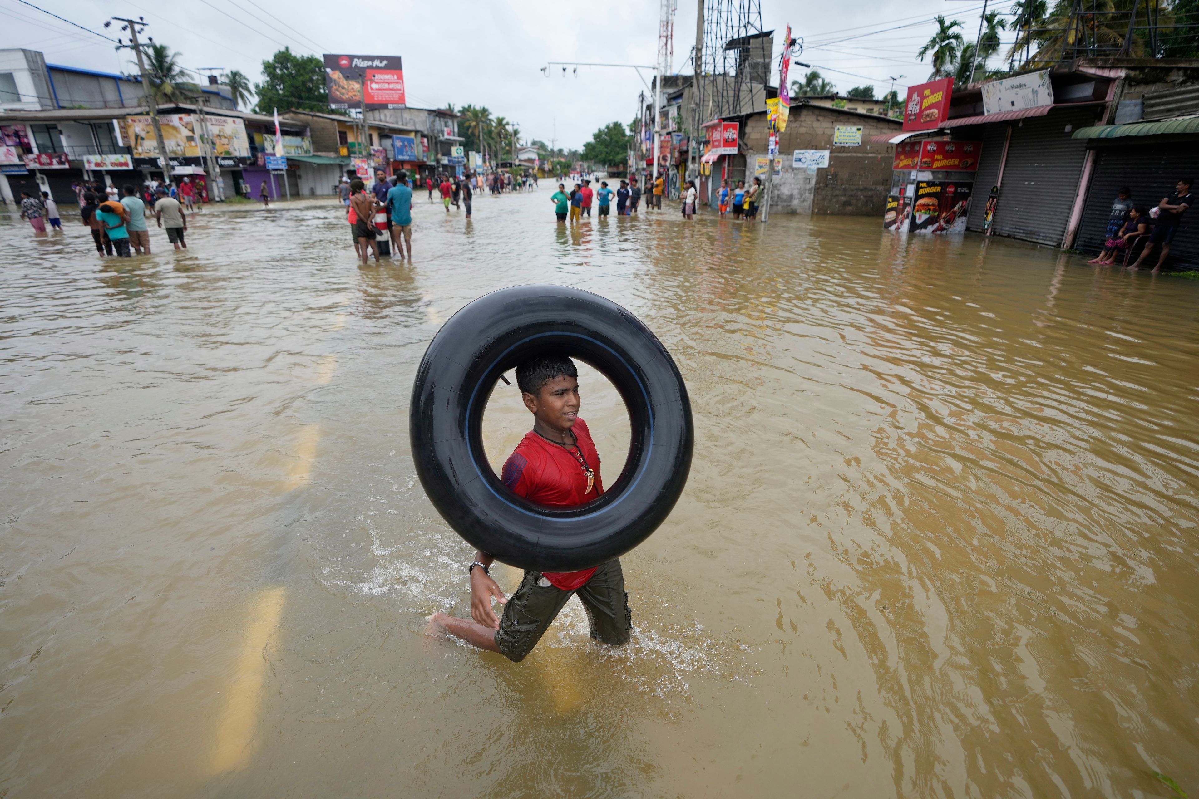 A boy plays with an inflatable rubber tube in a flooded street in Biyagama, a suburb of Colombo, Sri Lanka, Monday, Jun. 3, 2023. Sri Lanka closed schools on Monday as heavy rains triggered floods and mudslides in many parts of the island nation, killing at least 10 people while six others have gone missing, officials said.