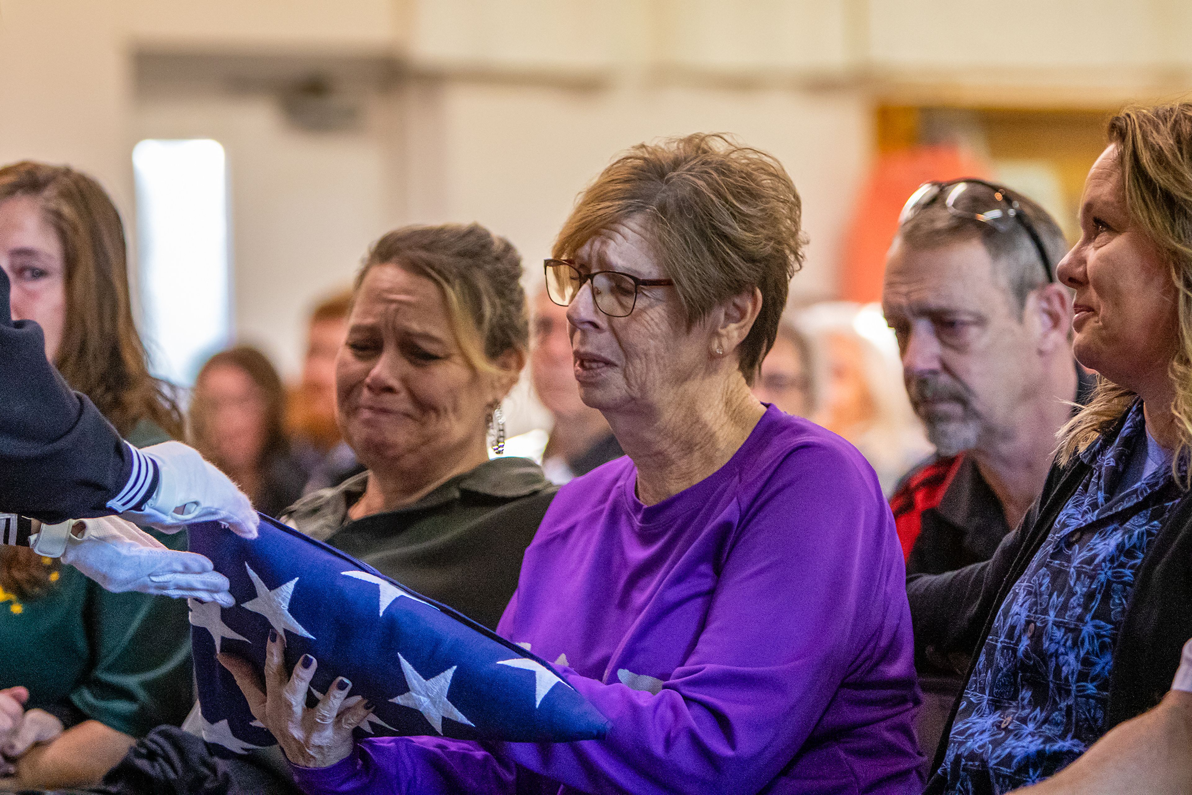 Lona Hirschel accepts an American flag from a Navy sailor Saturday on behalf of her late husband and Navy veteran Wayne Hirschel at his memorial in the Bennett Building of the Asotin County Fairgrounds in Asotin. Over 300 people attended the memorial to honor and remember Hirschel’s life, who passed away on Nov. 11 at the age of 75.