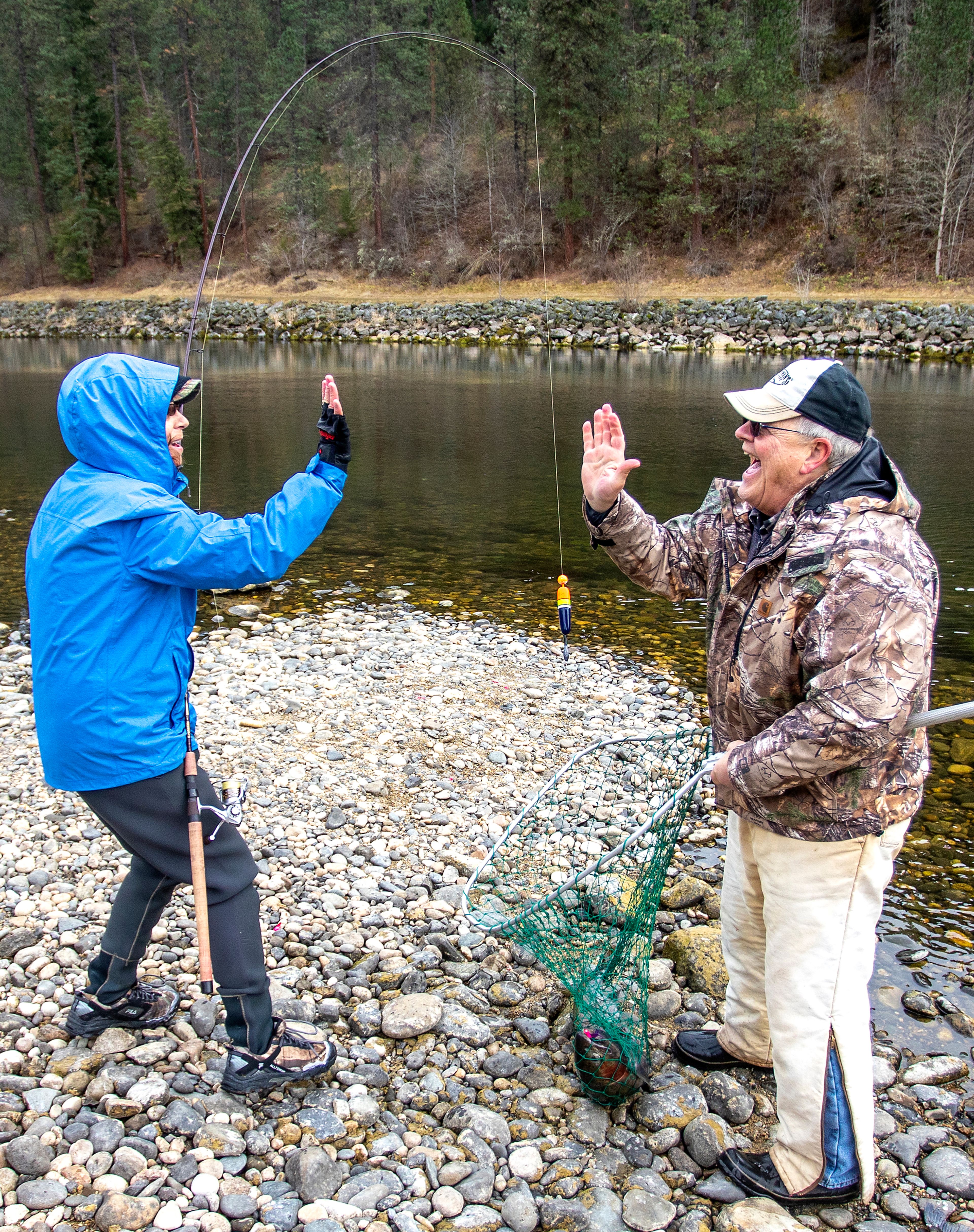 Marcia Trussell goes in for a high-five with Ted Mordhorst after she reeled in a steelhead that Mordhorst was able to net while fishing on the Clearwater River nearby Dworshak Dam on Wednesday in Ahsahka.