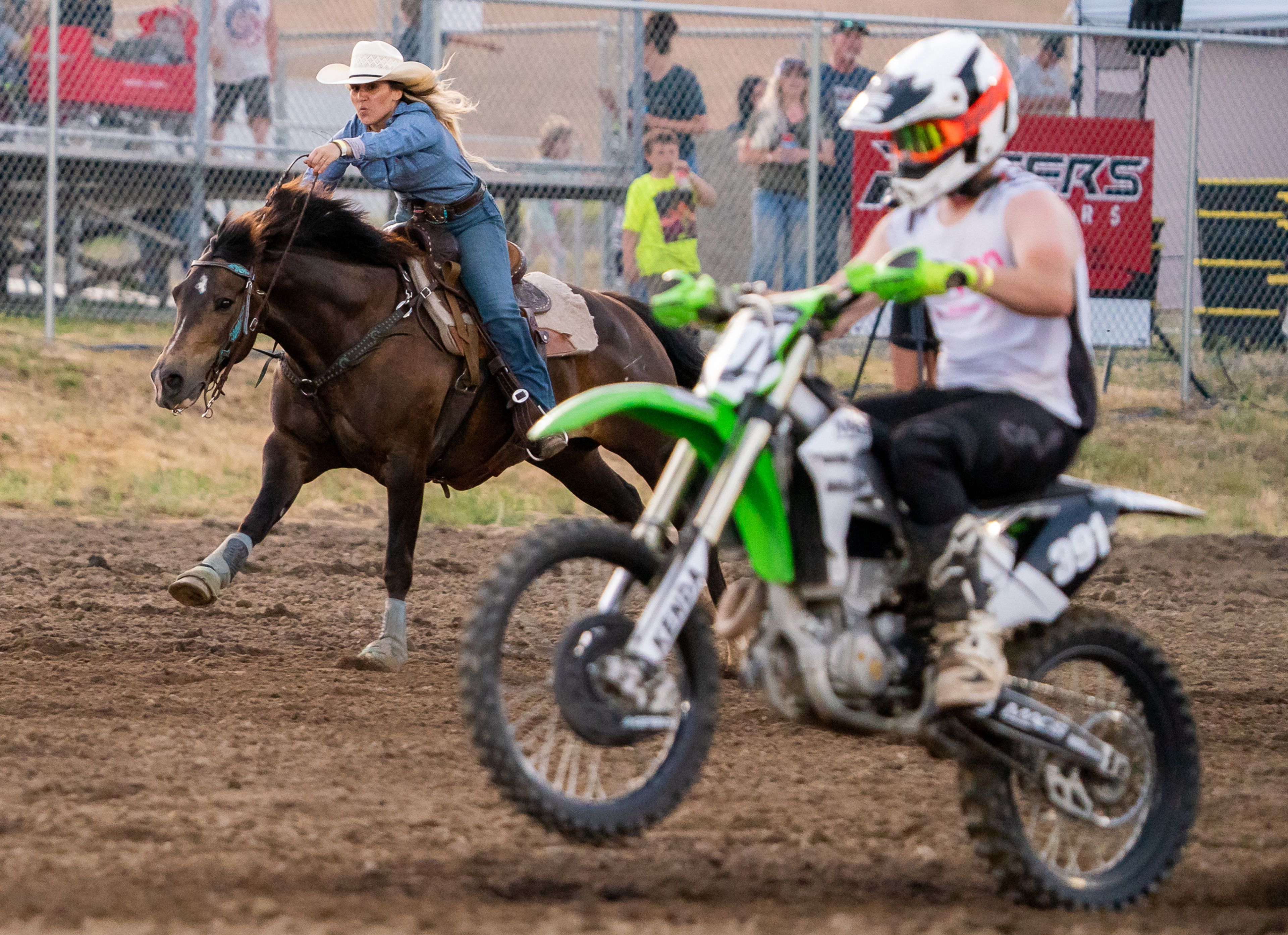 Horse rider Kenzi Triplet, left, is passed by a motorcycle rider in a head-to-head race during the Horsepower vs Horse Power event Saturday evening at ECMX Park in Lewiston.