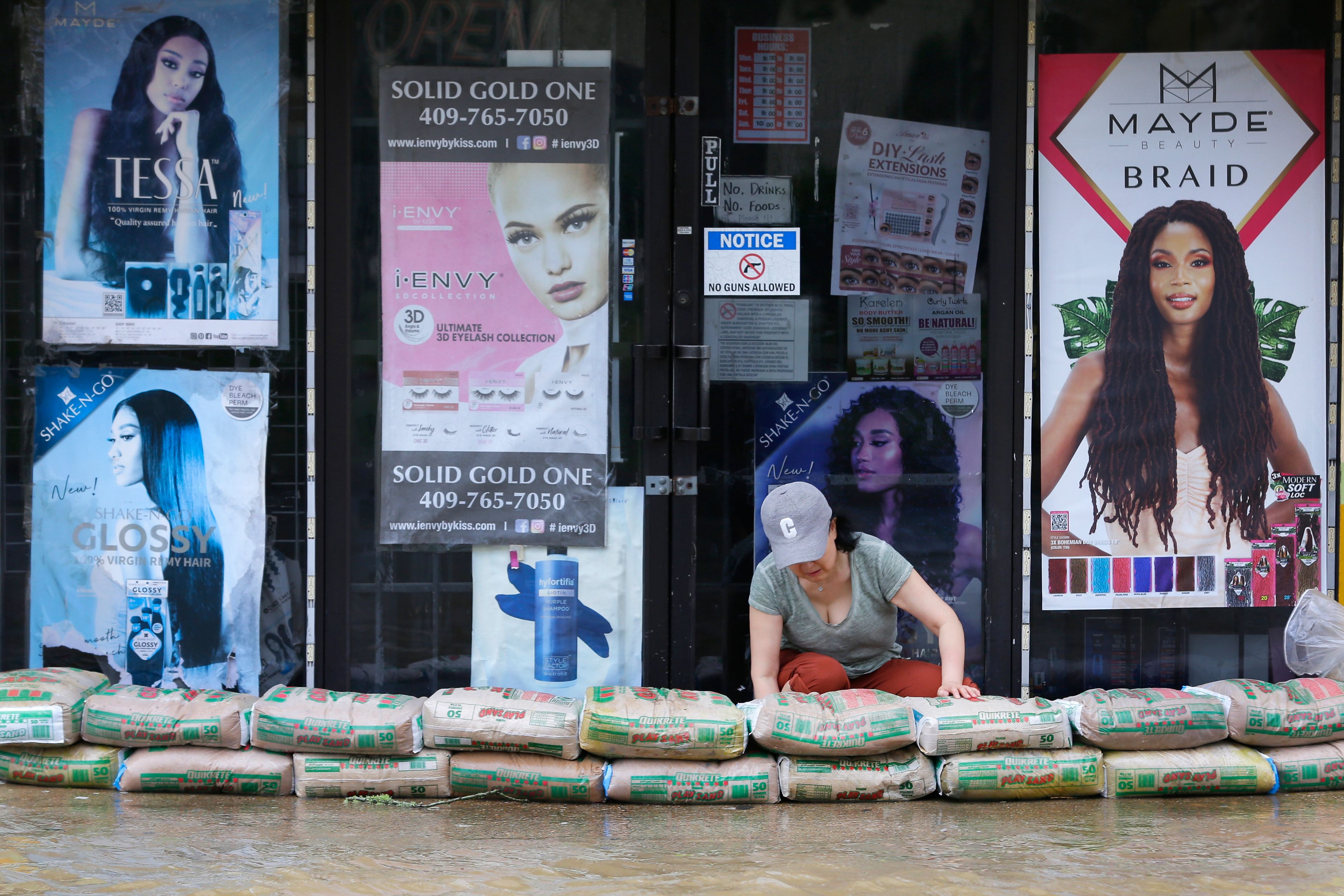 A shop owner piles sandbags around the entrance as street flooding approaches the building after Hurricane Beryl moved through Monday, July 8, 2024, in Galveston, Texas. (AP Photo/Michael Wyke)