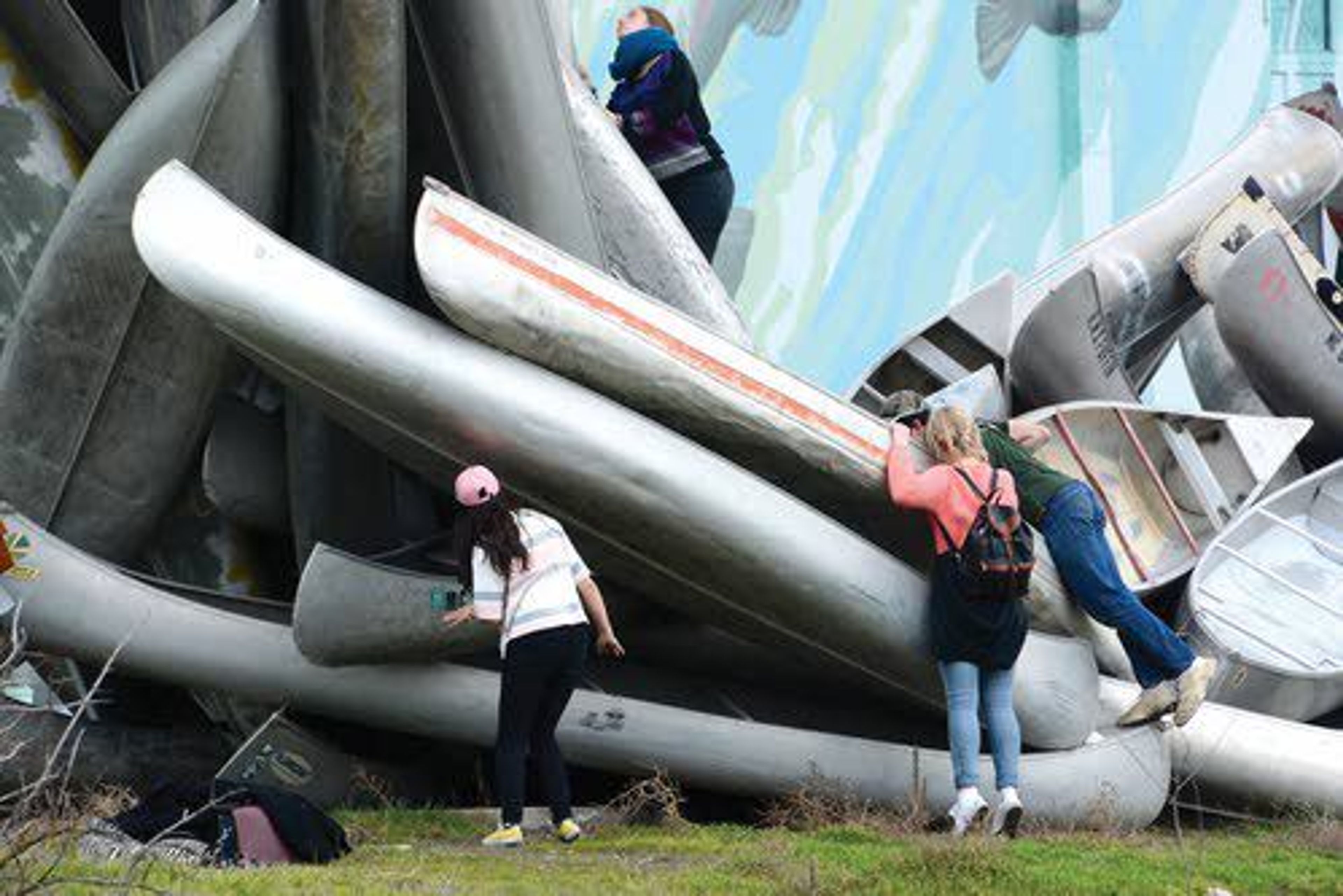 Several passers-by get a close-up look at the canoe wave sculpture by Chris Fennell near the levee ponds in downtown Lewiston on Monday.