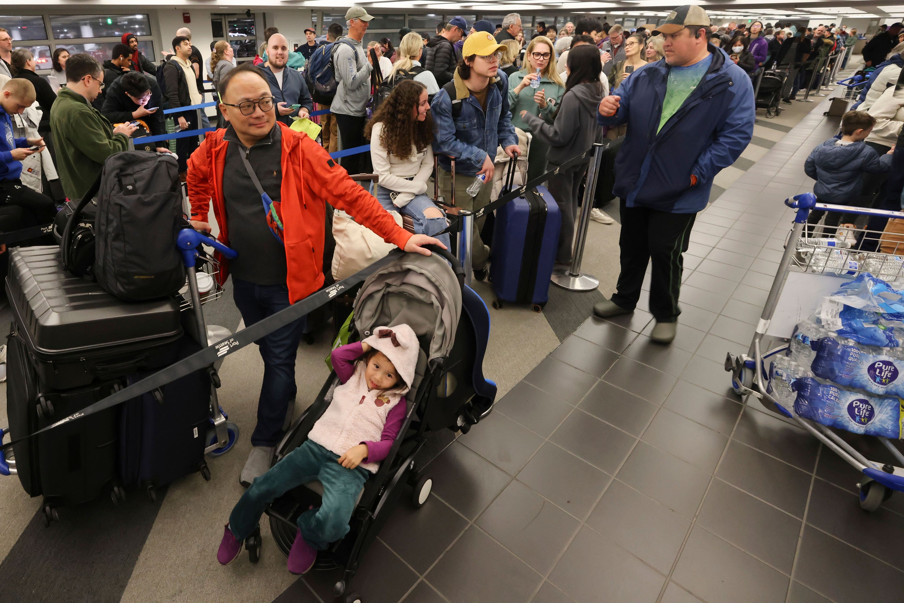 Kelvin Lau, left, waits with his family, including daughter Chloe, 3, to rebook a canceled Alaska Airlines flight, Saturday, Jan. 6, 2024, in SeaTac, Wash. Alaska Airlines canceled more than 100 flights after grounding Boeing’s fleet of 65 Max 9s for inspections following Friday’s emergency landing of a Boeing 737 Max 9 jetliner. (Karen Ducey/The Seattle Times via AP)