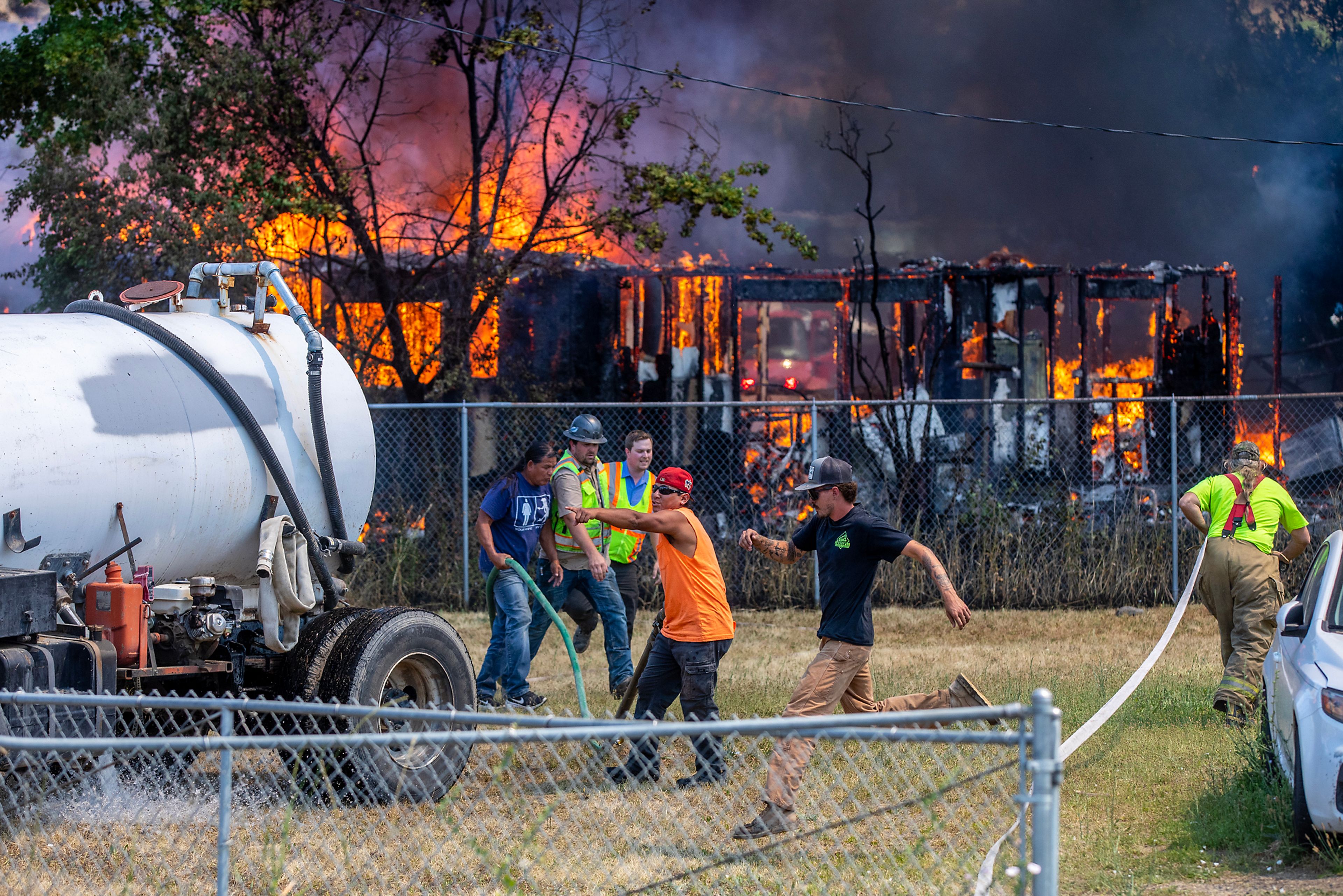 Firefighters work quickly to pull out hoses at the scene of a structure fire Friday on Lolo Street in Lapwai.