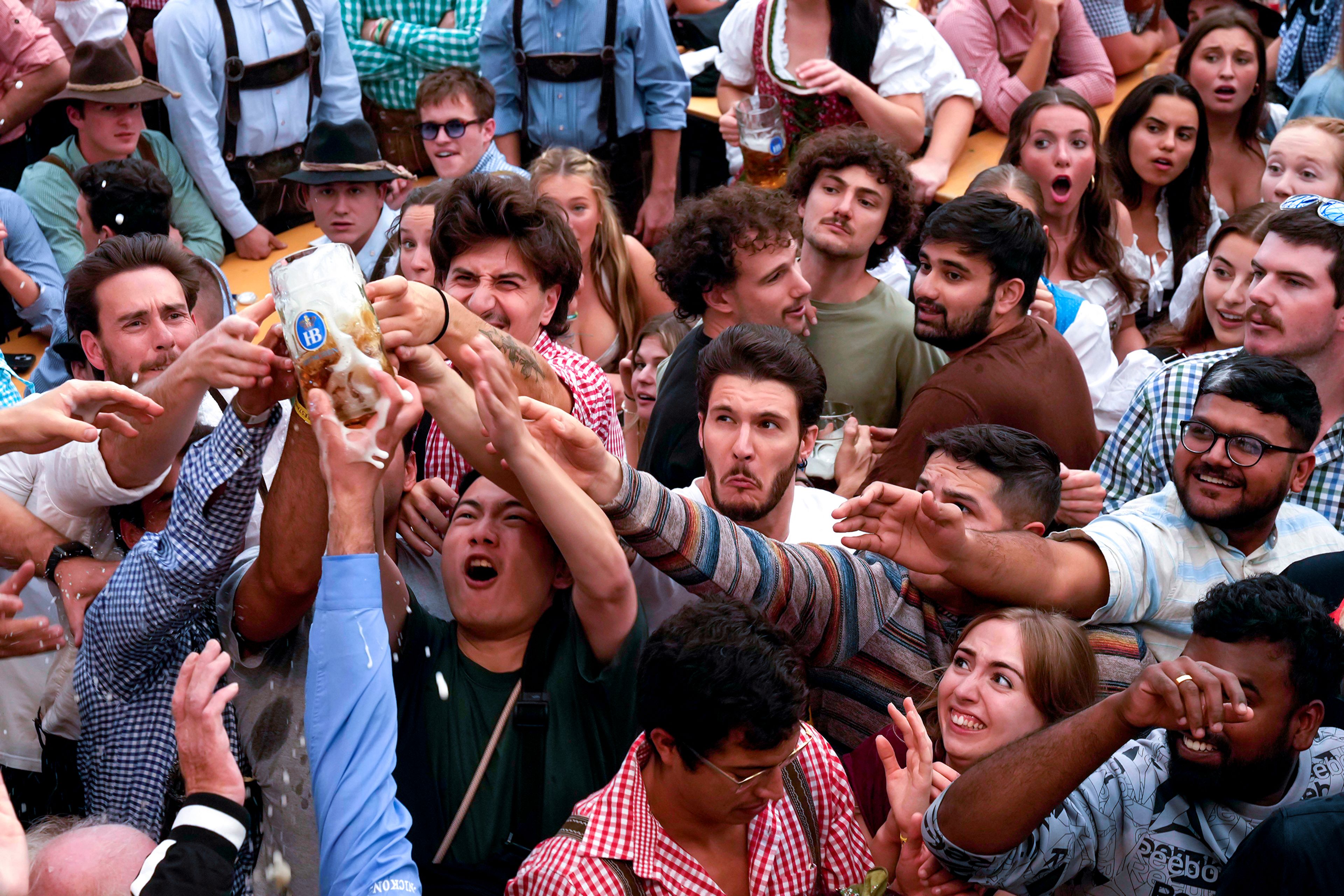 People reach for the first glasses of beer at the opening day of the 189th 'Oktoberfest' beer festival in Munich, Germany, Saturday, Sept. 21, 2024. (AP Photo/Matthias Schrader),