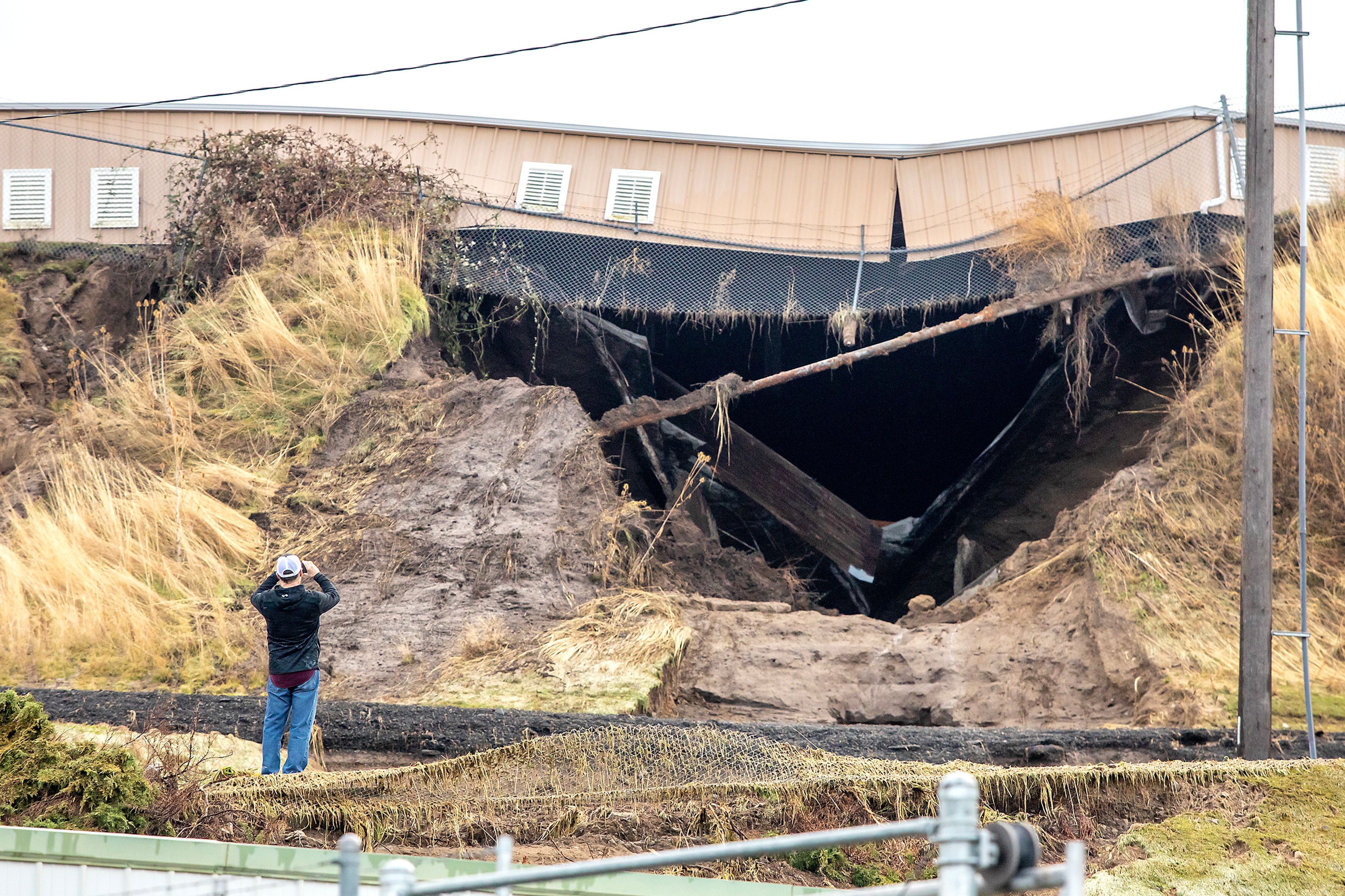 A man takes a photo of the water reservoir that burst off of 16th Avenue and 29th Street in Lewiston.