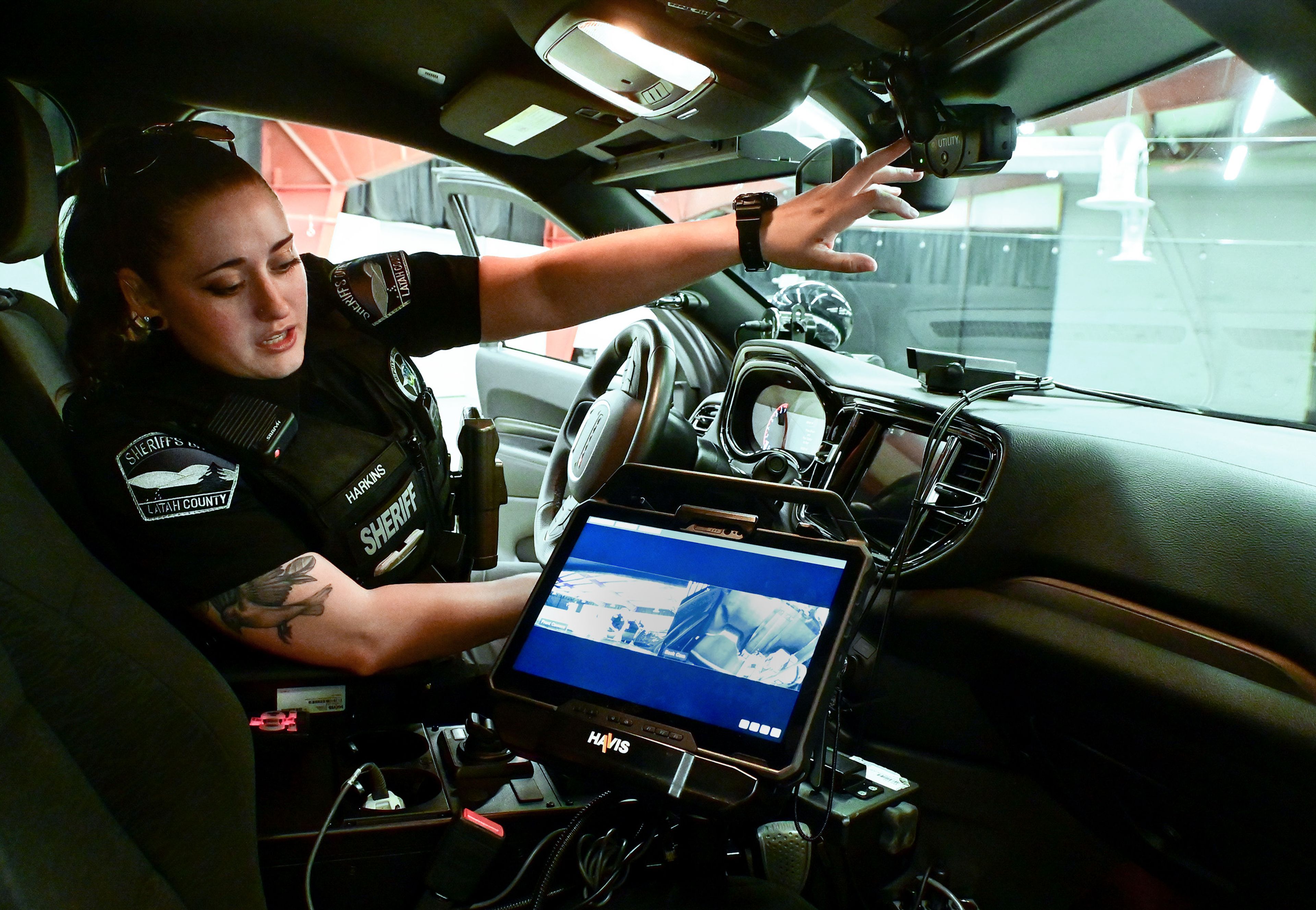 Riley Harkins, a Patrol Deputy with the Latah County Sheriff’s Office, points out a front facing camera outfitted in a patrol car, as well as a display screen for the camera and a second camera facing the back seat, on Thursday.