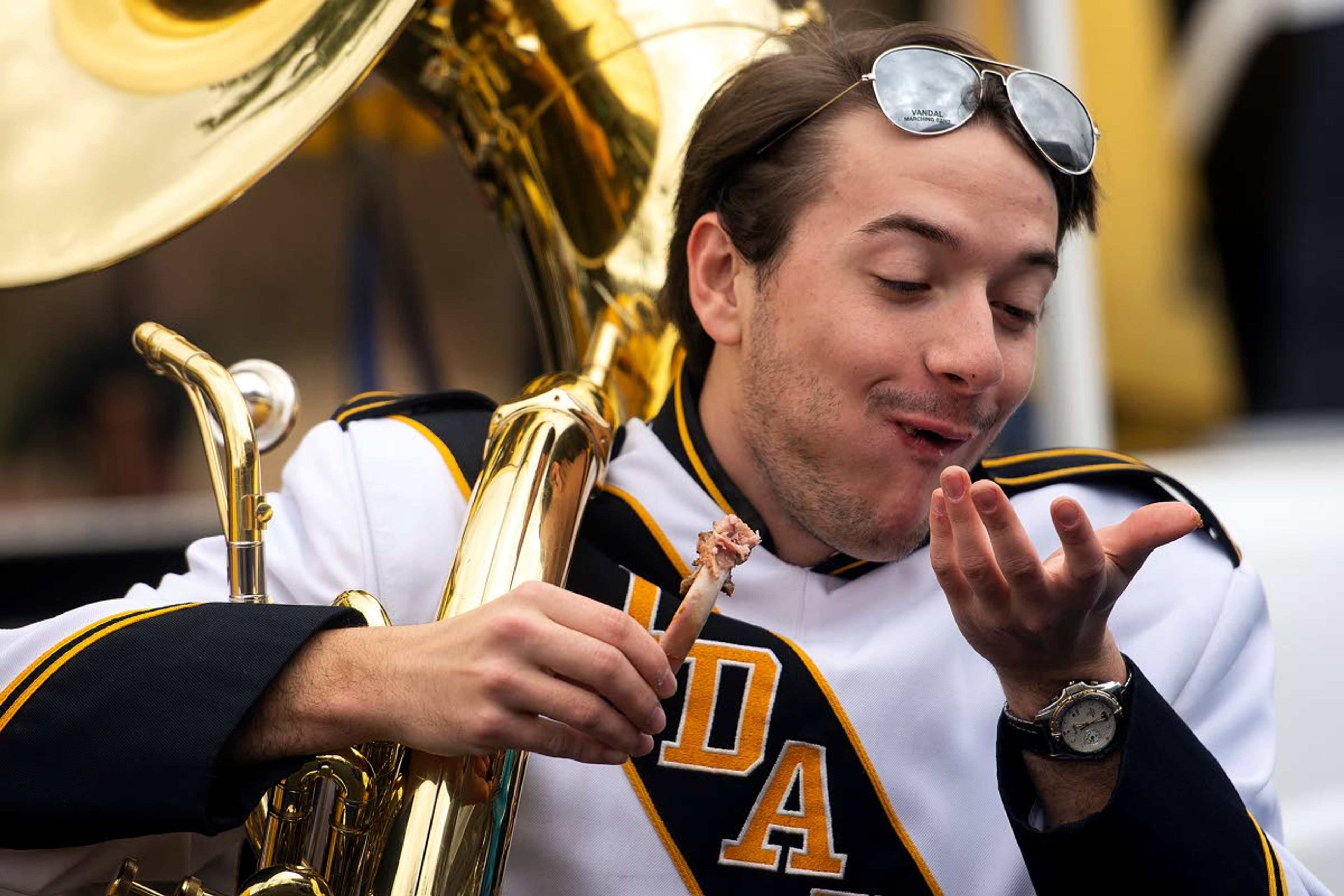 They never ask for food, but are always eager to receive tailgate treat, as Tim Malm scarfs down a rib after performing for a group of tailgaters on Saturday, Nov. 3.