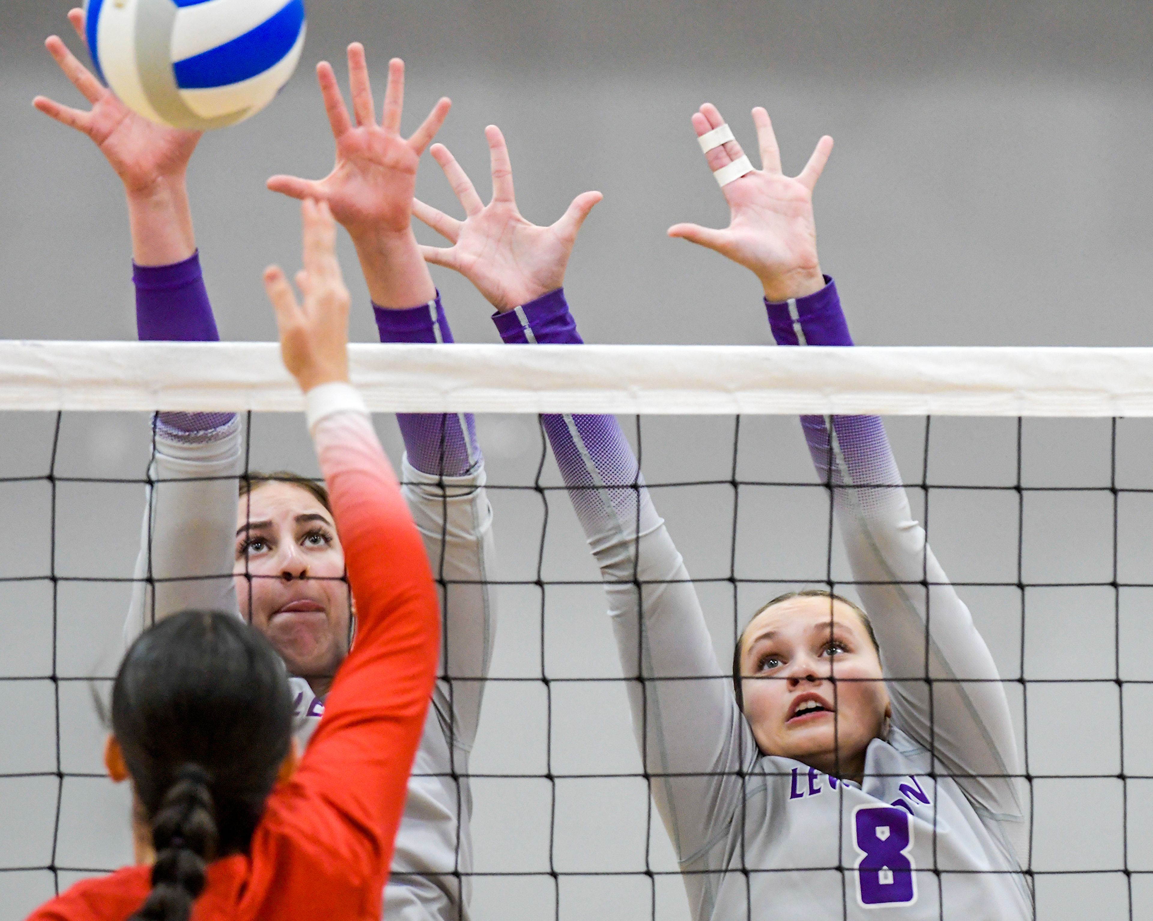 Lewiston middle blocker Hannah Huffman, left, and setter Piper Blinn leap up to block a Sandpoint hit during a volleyball game Thursday in Lewiston.,