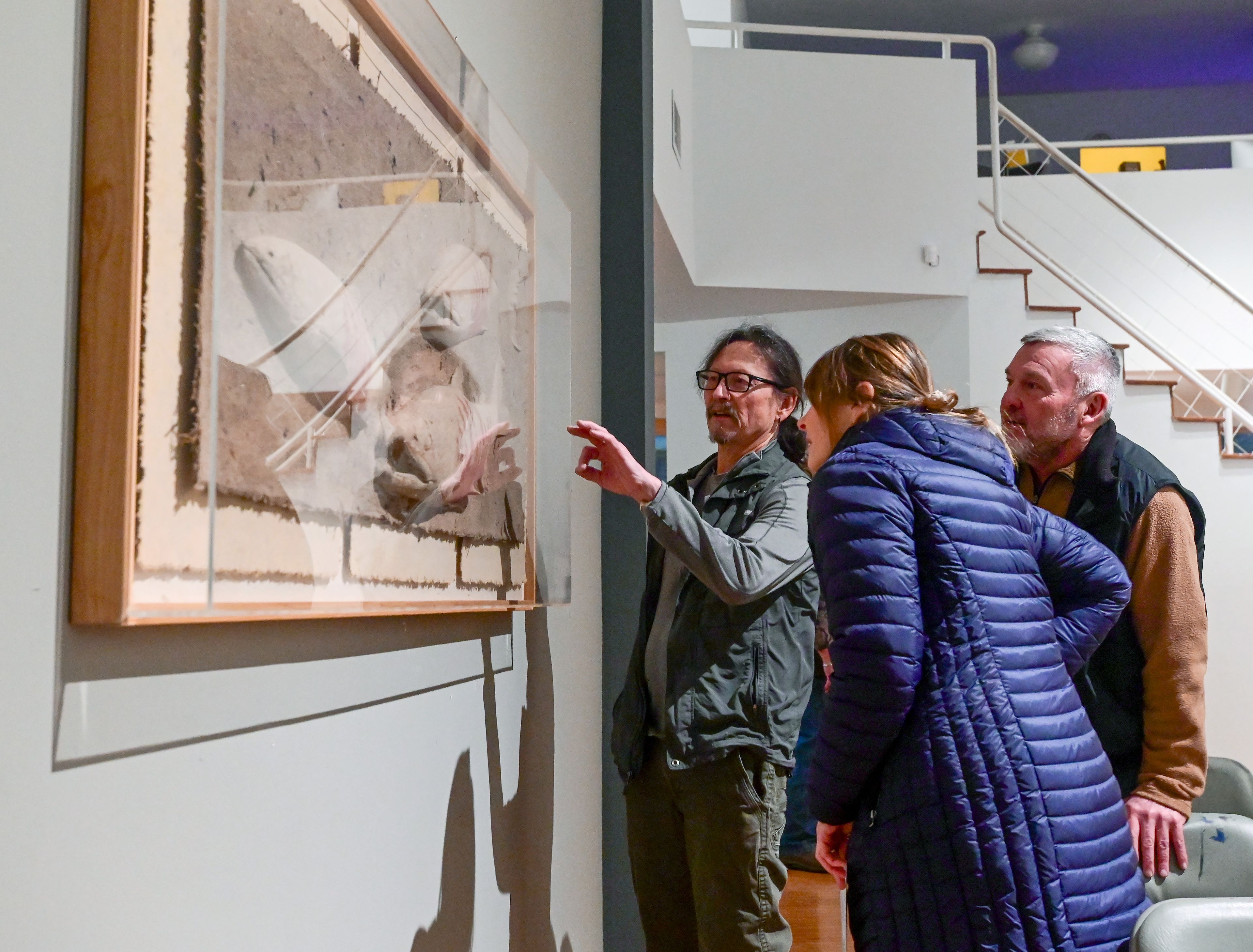 Artist Lonnie Hutson, left, points to a piece in his mock up of a possible future Moscow Contemporary show while speaking with Moscow residents Marci Stephens, center, and Chuck McDonell in Moscow on Thursday. The art gallery held a town hall and closing concert that evening.