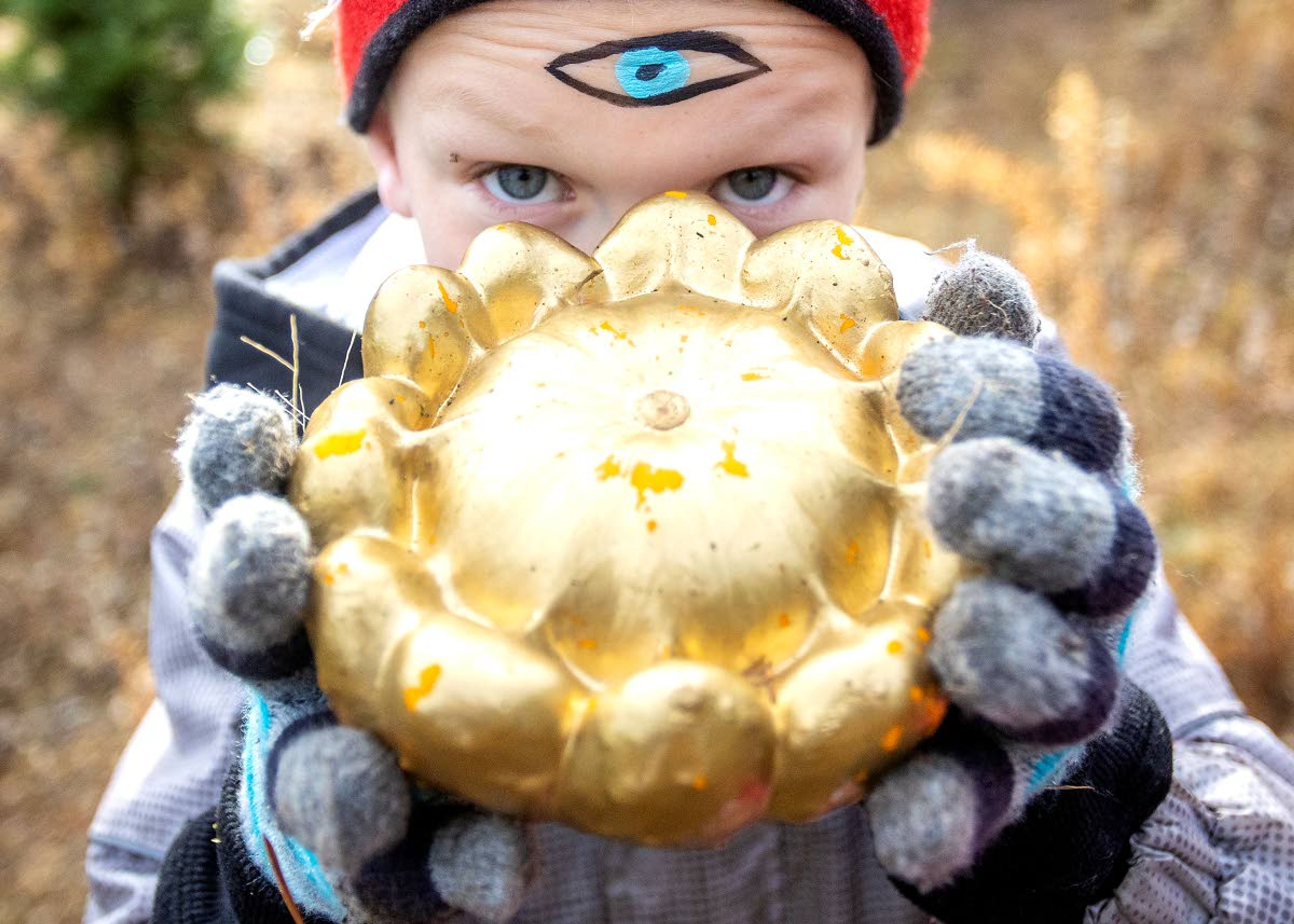 Austin Fletcher holds up his golden gourd which he found hidden among the trees and pumpkins with the help of his third eye that he had painted on his forehead at the pumpkin hunt.