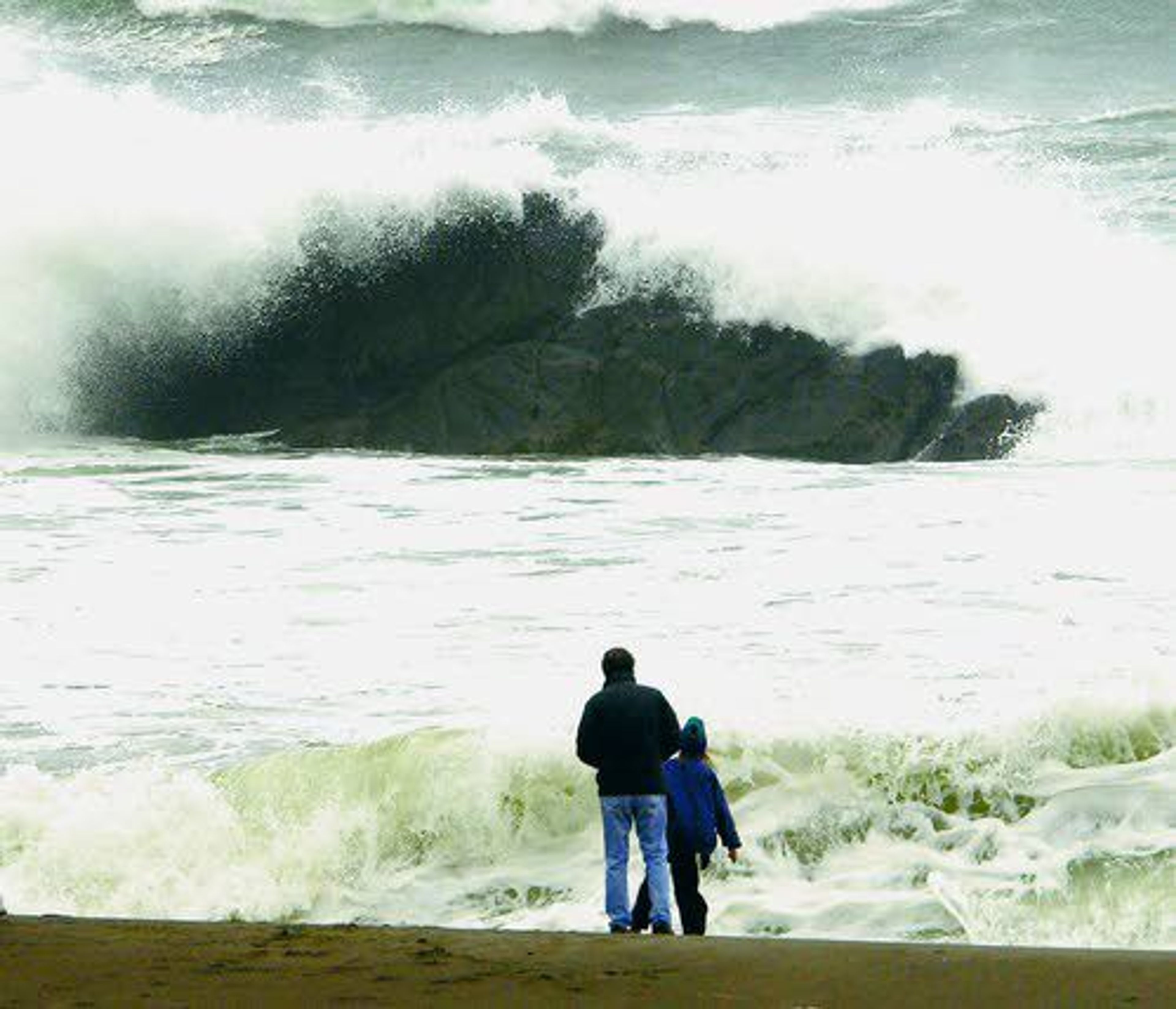 In this Nov. 28, 2001, file photo, beachcombers watch as storm-tossed waves crash over rocks near Depoe Bay, Ore. Since 1990, all major sneaker wave incidents have occurred between October and April, peaking in November and March. In that time, at least 21 people have been killed by sneaker waves on the Oregon coast, and several others have been severely injured.