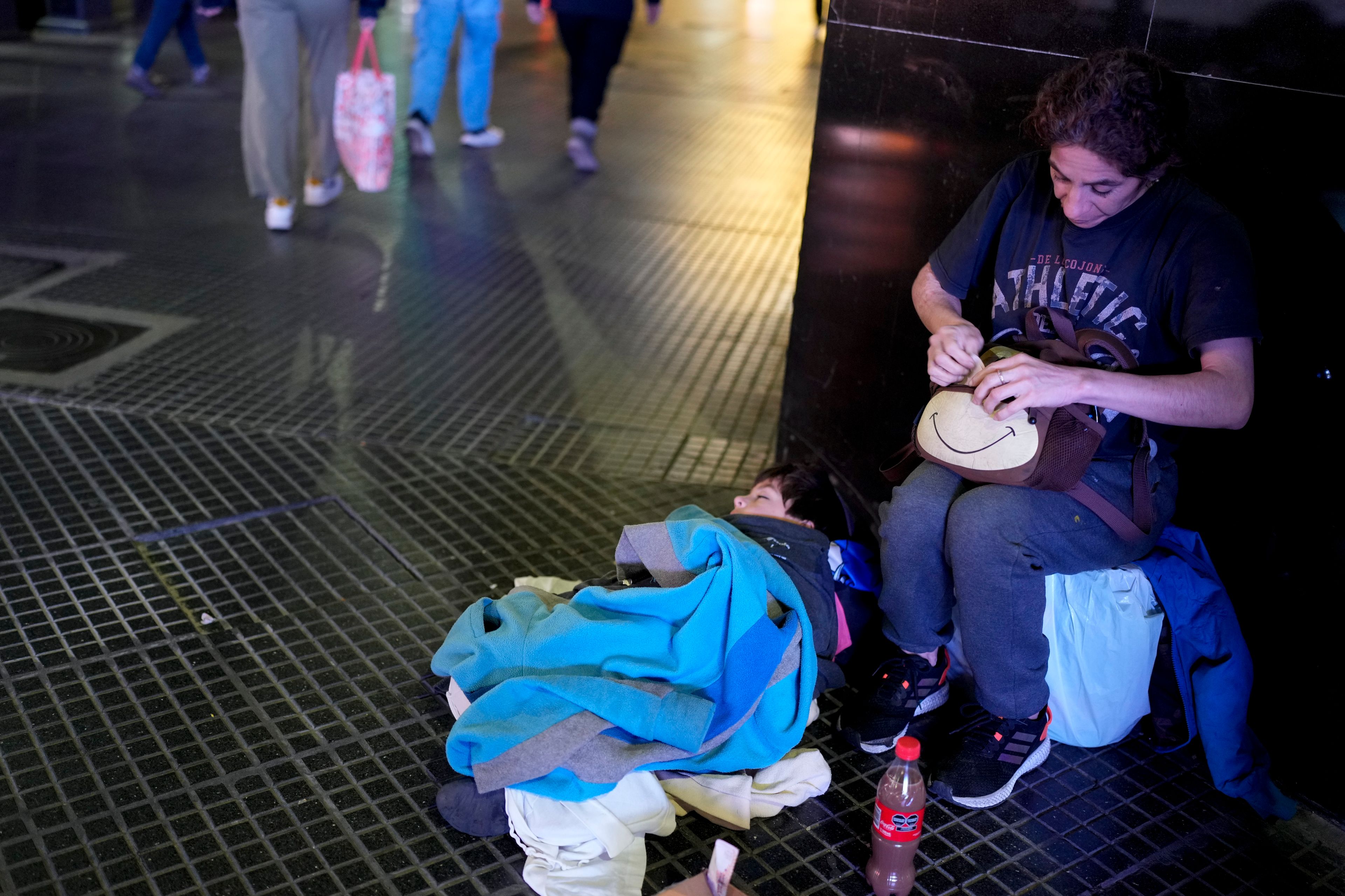 Cintia Barros' son Alessandre sleeps on the ground as she begs on a street corner sidewalk in downtown Buenos Aires, Argentina, Tuesday, Sept. 3, 2024. (AP Photo/Natacha Pisarenko)