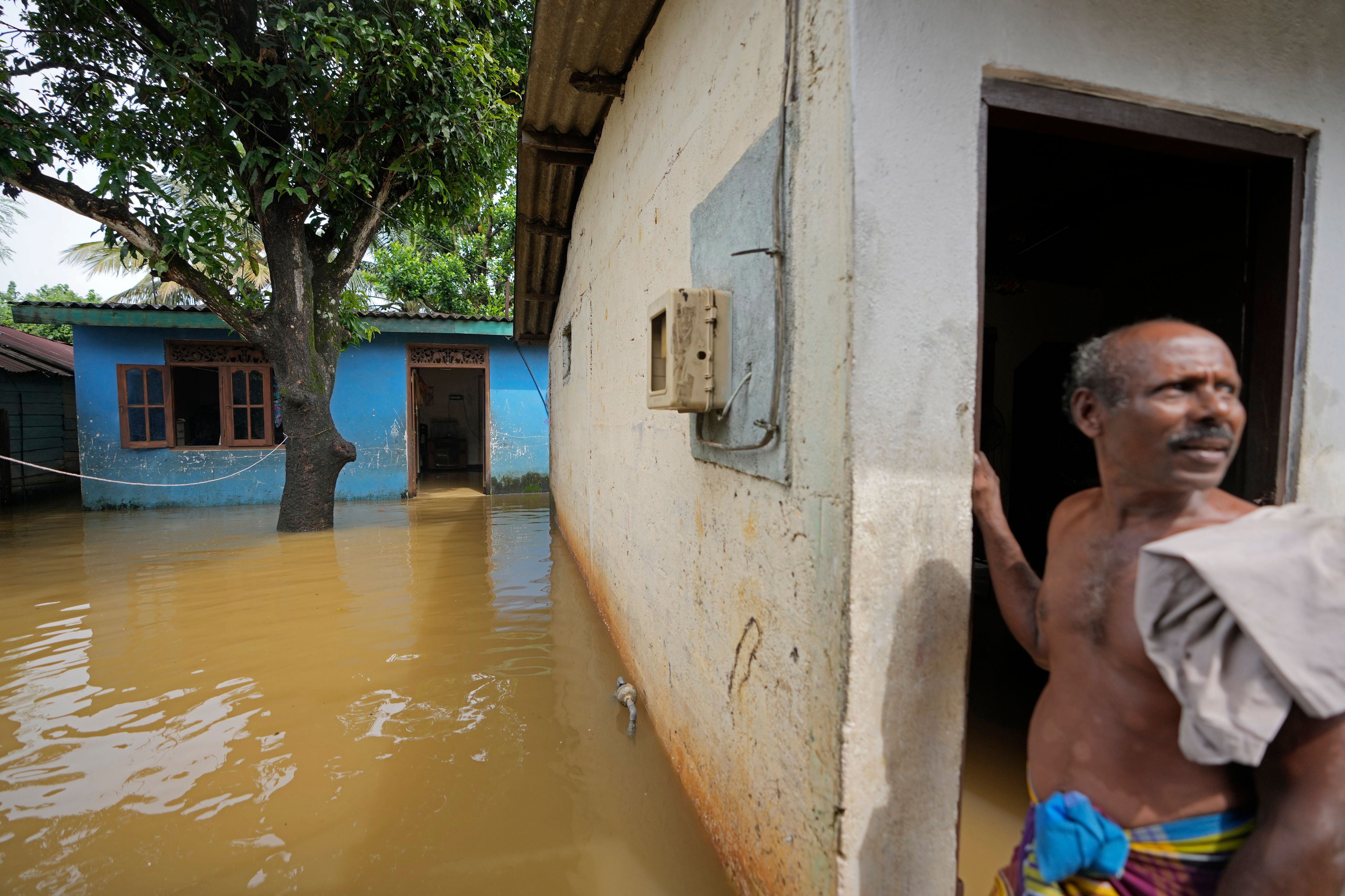 A man stands outside his house submerged with floodwaters in Kelaniya, a suburb of Colombo, Sri Lanka, Monday, June 3, 2024. Sri Lanka closed schools on Monday as heavy rains triggered floods and mudslides in many parts of the island nation, killing at least 10 people while six others have gone missing, officials said.