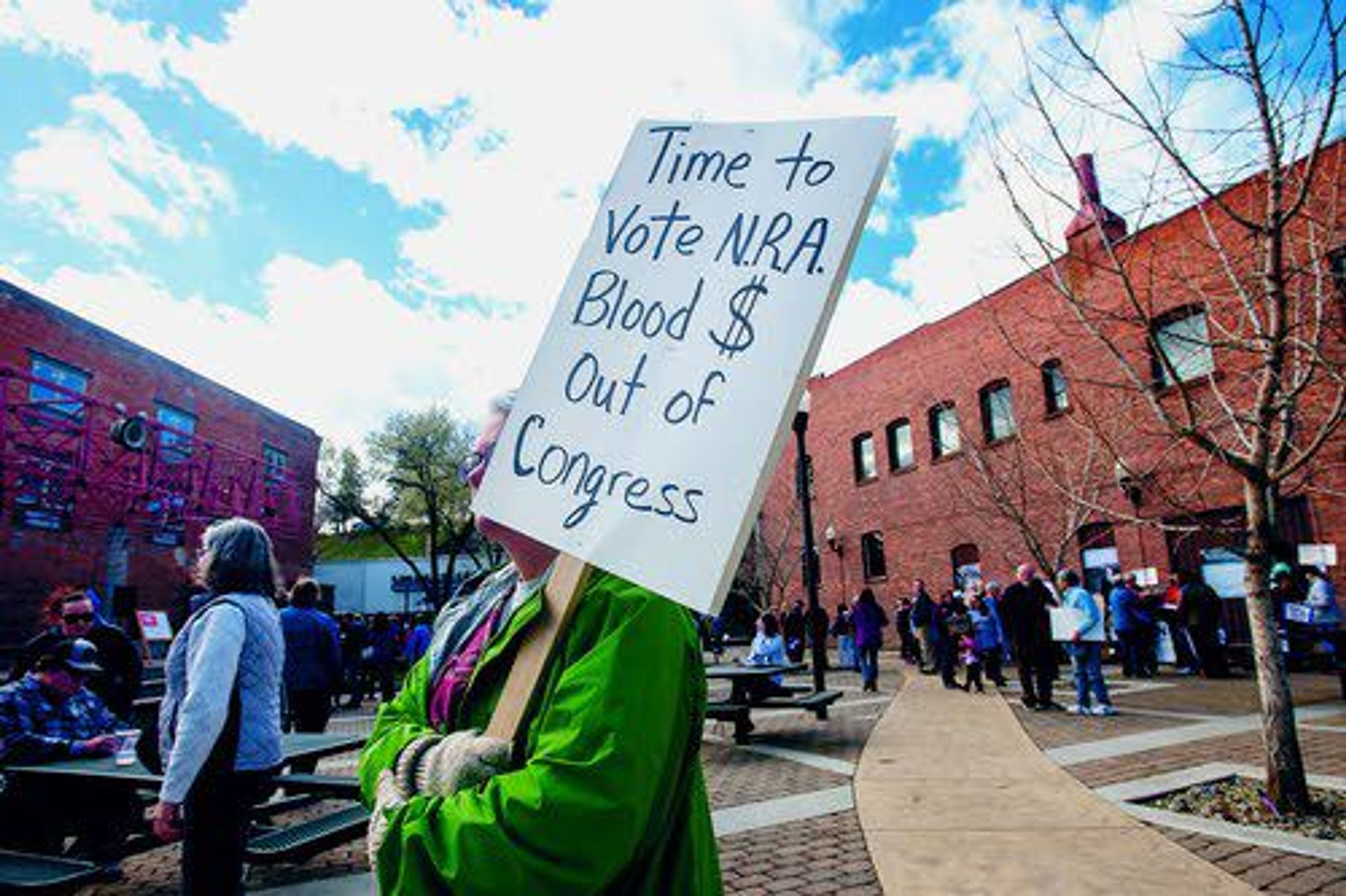 A woman walks through Brackenbury Square holding a sign during the March for Our Lives Rally in Lewiston.