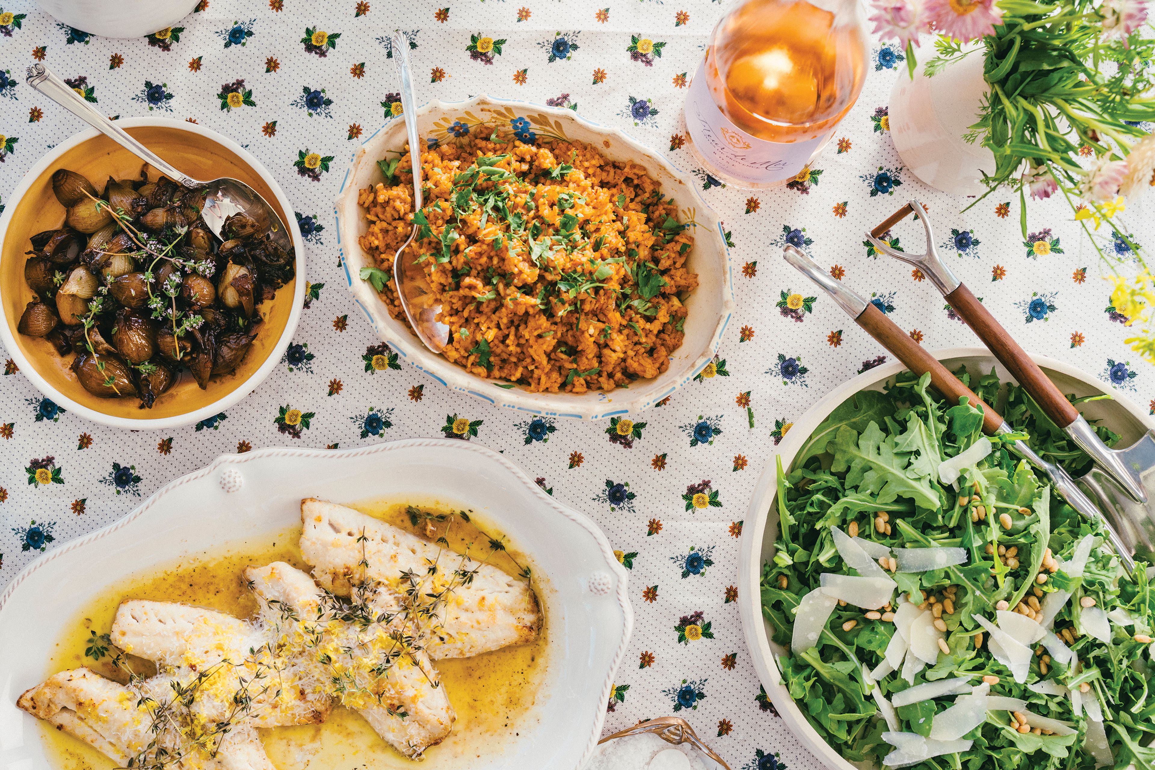 This image released by Celadon Books shows a table spread featuring a red rice dish, top center, from the cookbook "Does This Taste Funny: Recipes Our Family Loves" by Stephen Colbert and Evie McGee Colbert. (Eric Wolfinger/Celadon Books via AP)