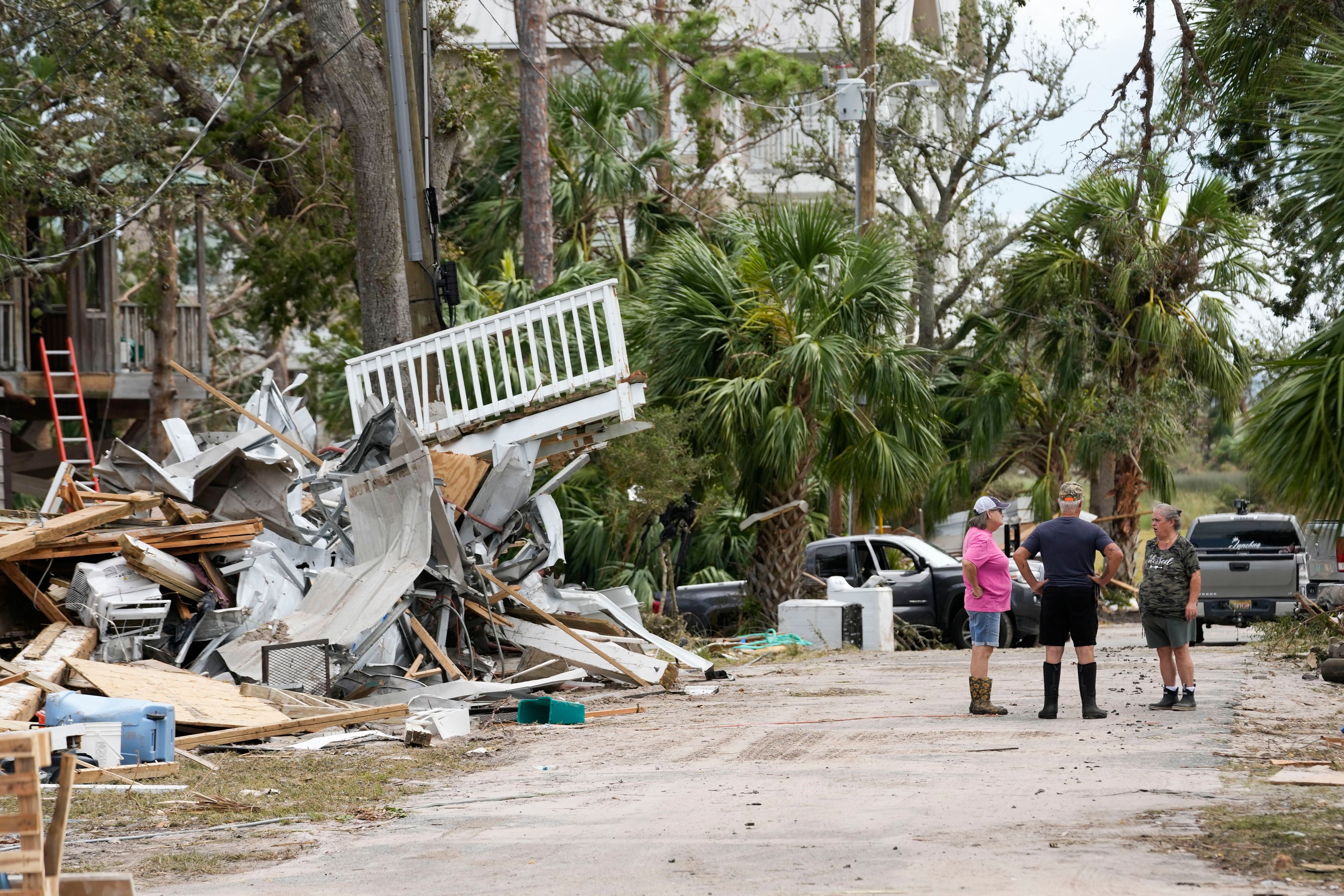 Frankie Johnson, left, and her husband, Mark Johnson, talk with fellow resident Charlene Huggins, right, amid the destruction in the aftermath of Hurricane Helene, in Horseshoe Beach, Fla., Saturday, Sept. 28, 2024. (AP Photo/Gerald Herbert)