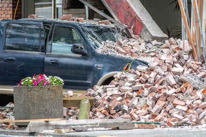 Car under rubble after crashing into a building