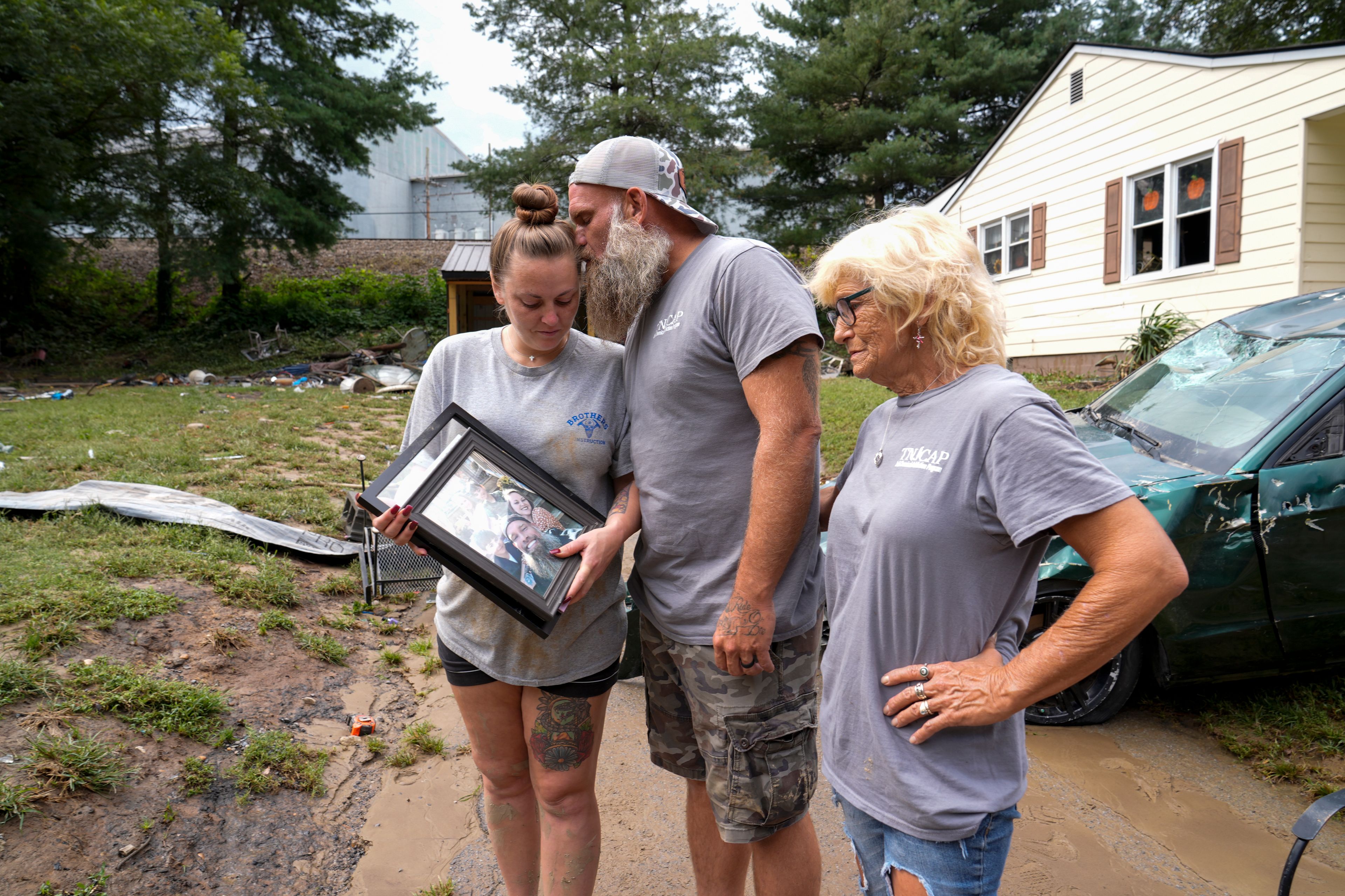 Dustin Bentley, center, kisses his wife Jennifer Bentley, left, after retrieving family photos from their flood-damaged home in the aftermatch of Hurricane Helene as his mother Janet Sams looks on Saturday, Sept. 28, 2024, in Newport, Tenn. (AP Photo/George Walker IV)