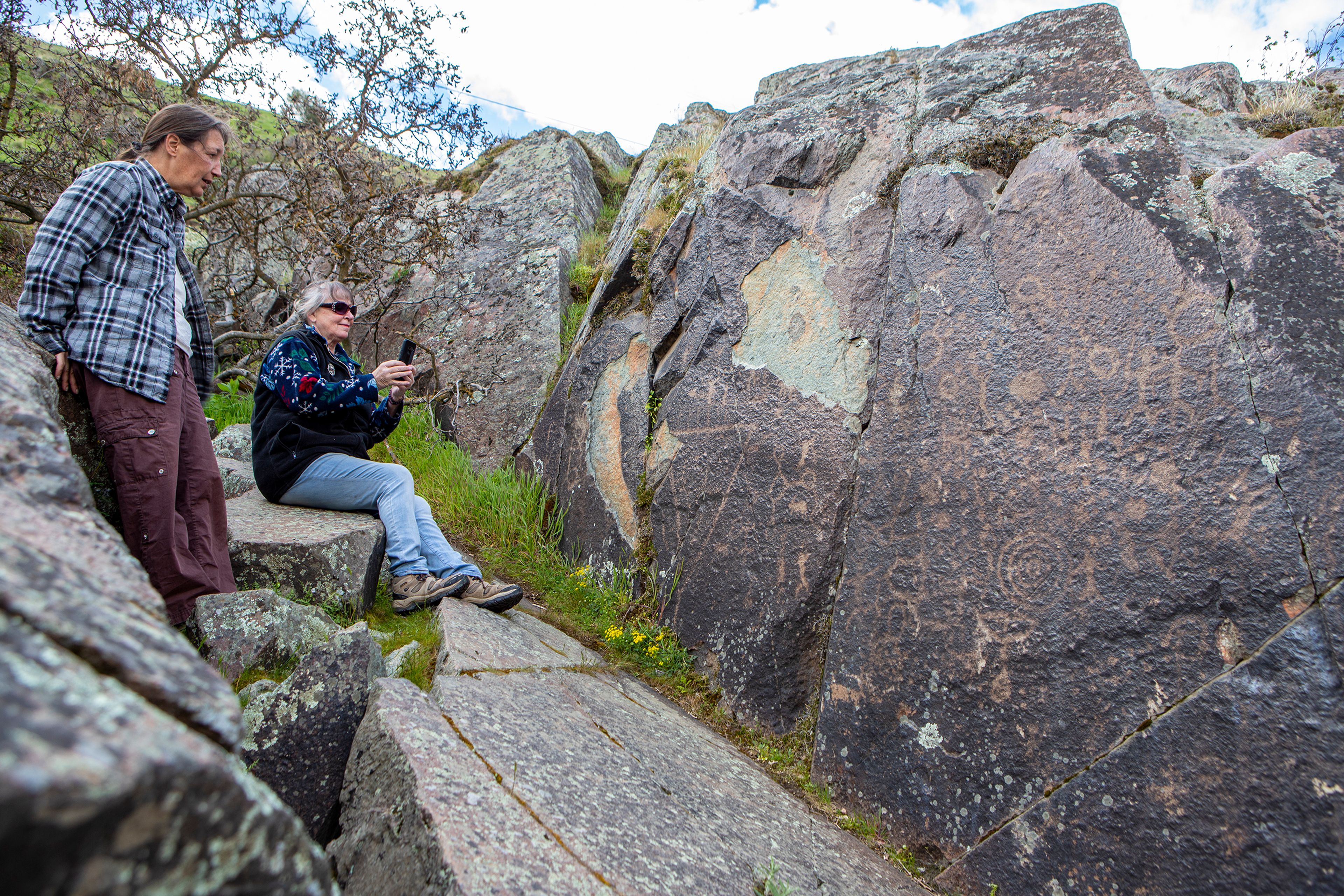 Cindy Reisinger, right, of Pomeroy, and her friend Anna Medici, of Maine, take photos of the petroglyphs etched into the rocks at Buffalo Eddy along the Snake River, 18 miles south of Asotin. These drawings left behind by the Nez Perce people give evidence of their strong connection with the animals and land.