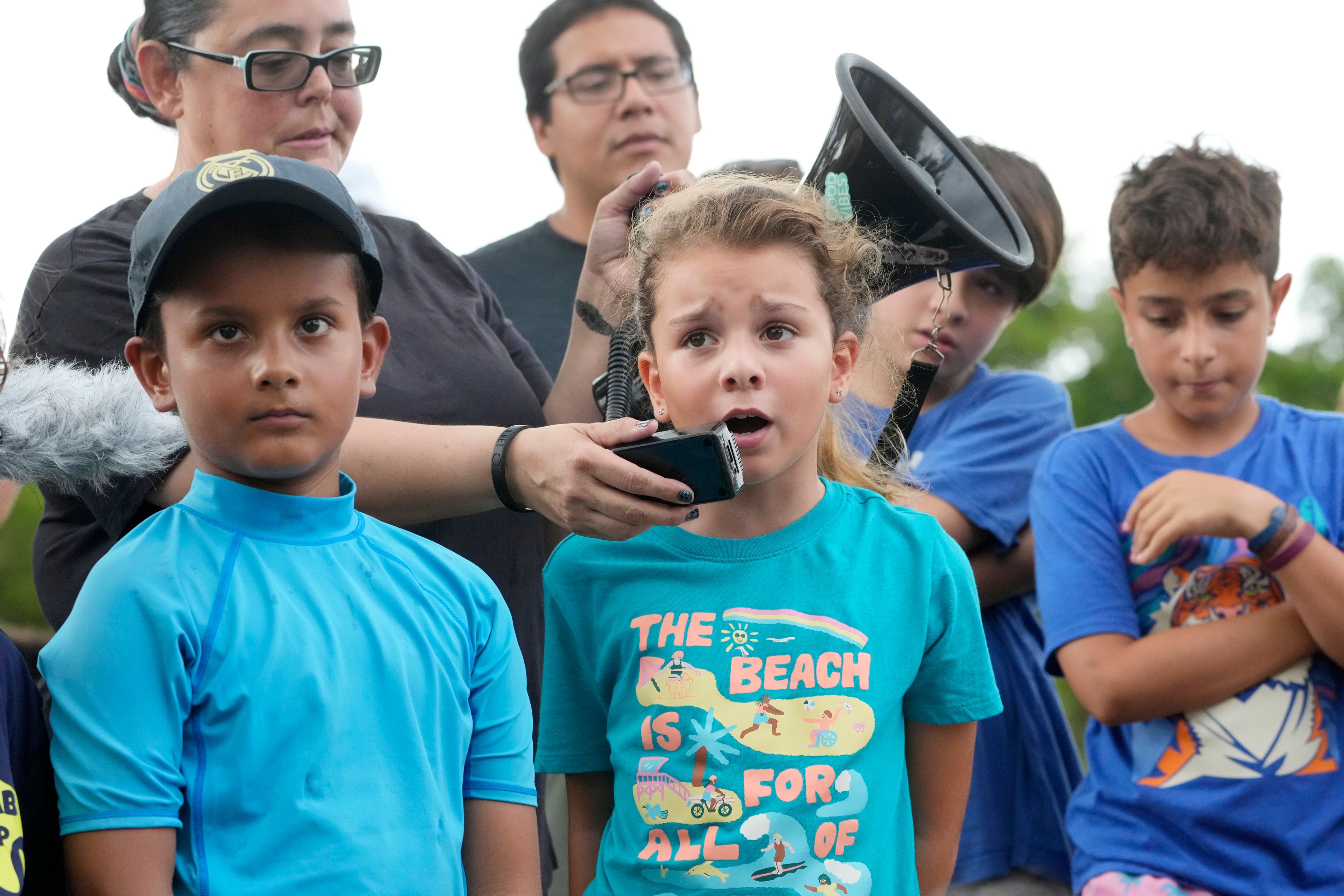 Helena Lourenco, center, 8, speaks out during a protest against Gov. Ron DeSantis' plan to develop state parks with business ventures such as golf courses, pickleball courts and large hotels, during a demonstration at Oleta River State Park, Tuesday, Aug. 27, 2024, in North Miami Beach, Fla.