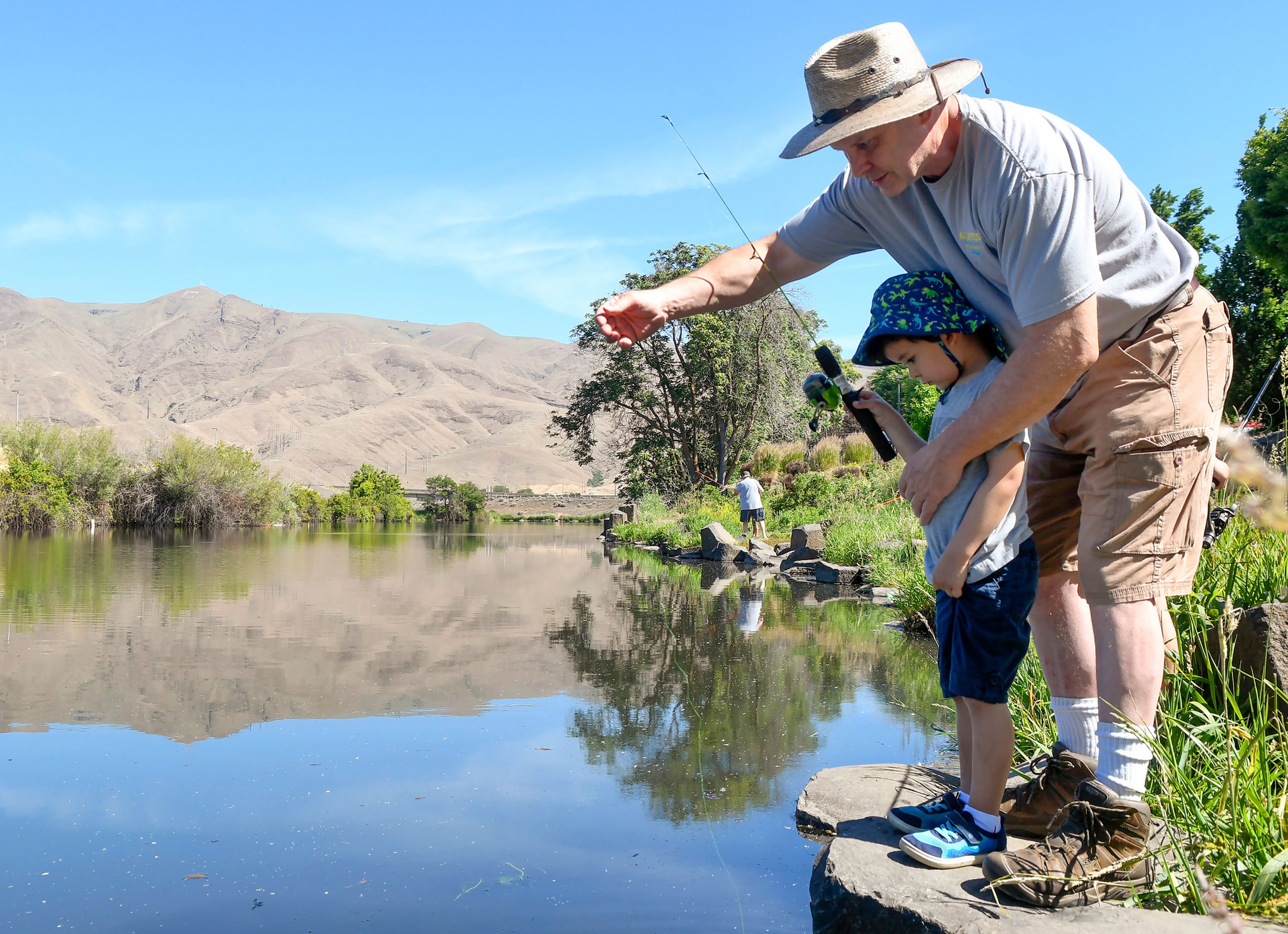 Conor O’Callaghan, 4, is helped by father John O’Callaghan, of Lewiston, to drop a fishing line in Kiwanis Park Pond on their first family fishing expedition on Saturday, Idaho's Free Fishing Day, in Lewiston.