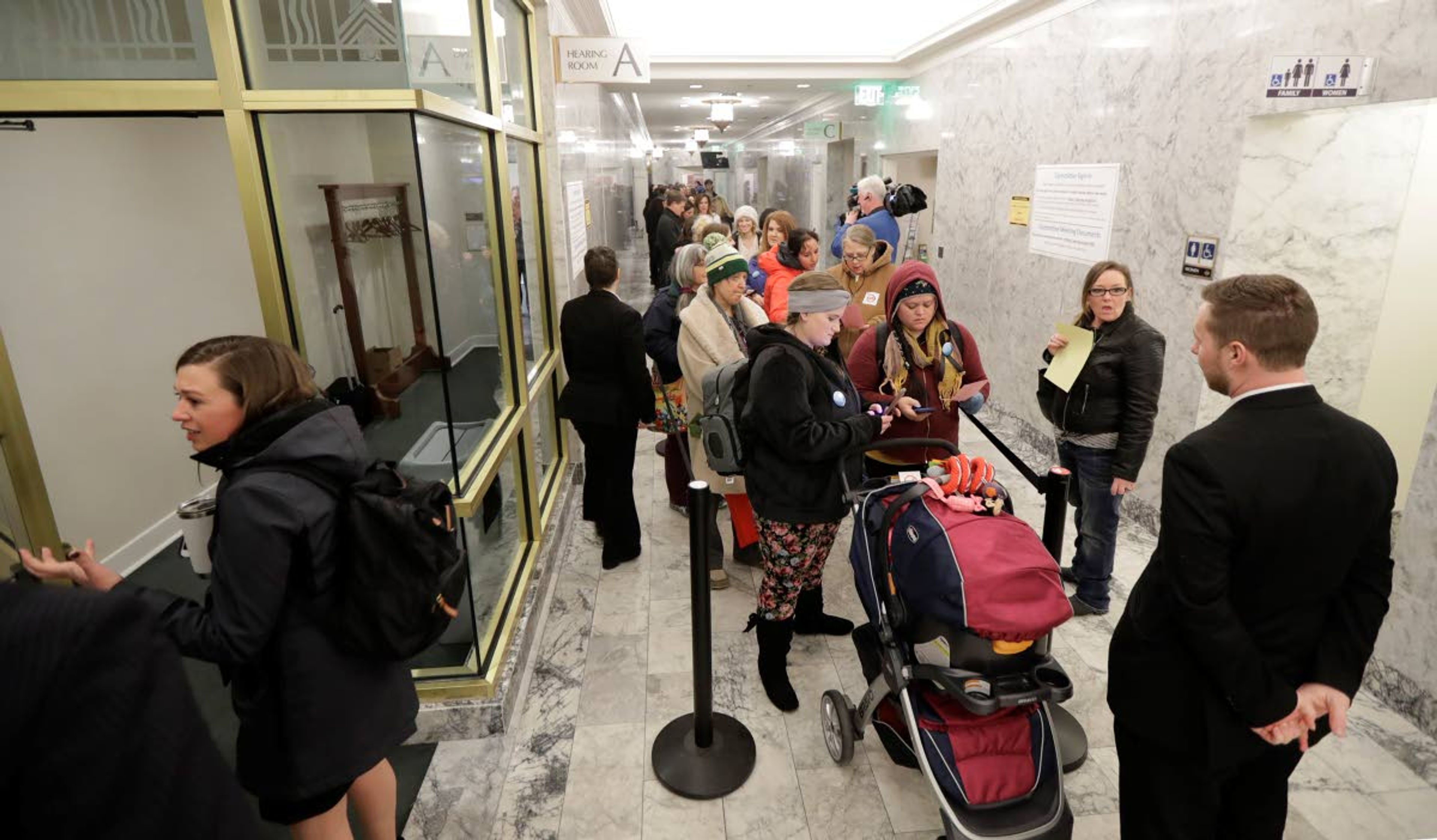 People line up in a hallway, Friday, Feb. 8, 2019, before a public hearing before the House Health Care & Wellness Committee at the Capitol in Olympia, Wash. Amid a measles outbreak that has sickened people in Washington state and Oregon, lawmakers heard public testimony on a bill that would remove parents' ability to claim a philosophical exemption to opt their school-age children out of the combined measles, mumps and rubella vaccine. (AP Photo/Ted S. Warren)