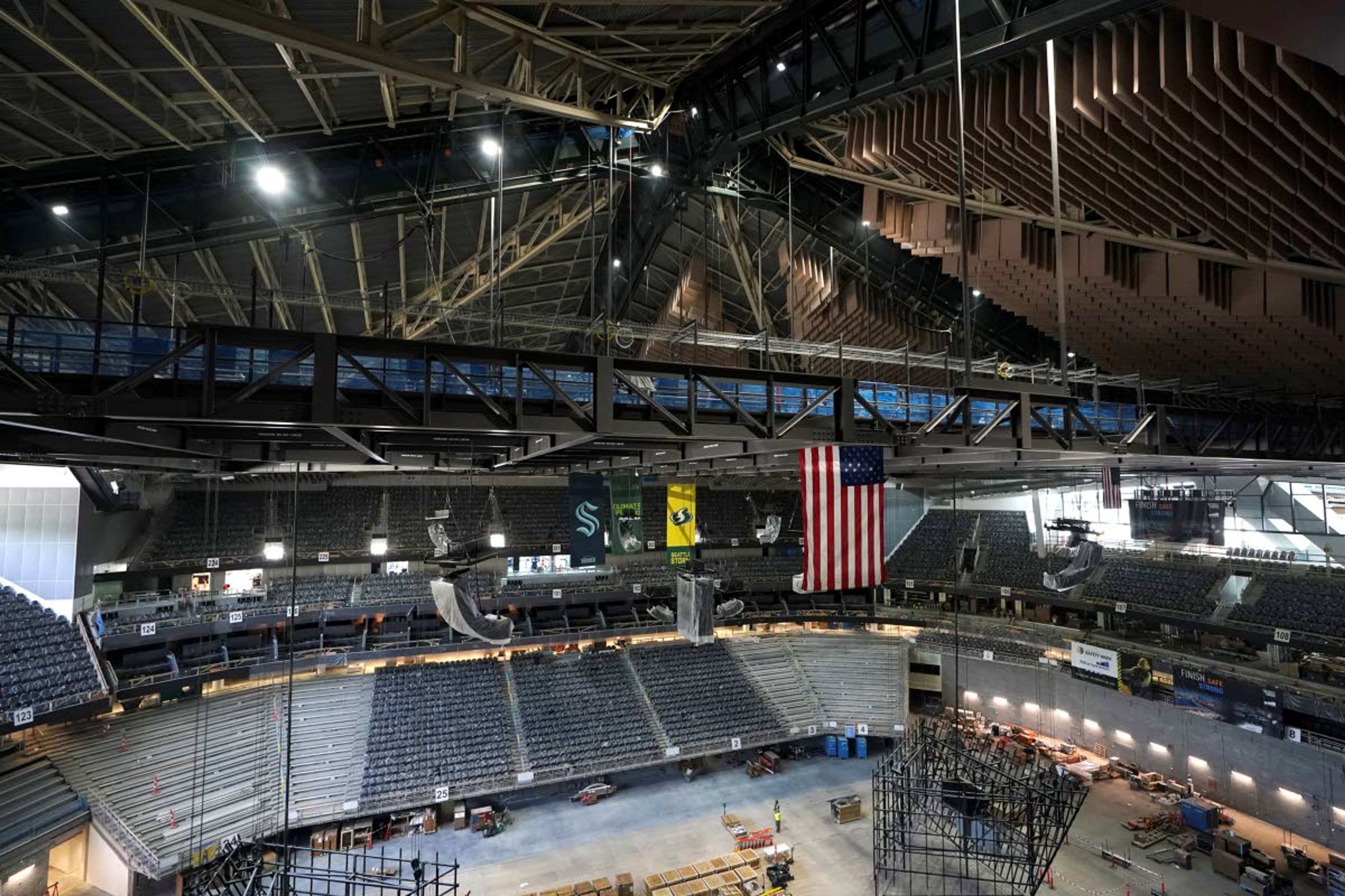 The interior beams of the historic peaked roof of the Climate Pledge Arena rise above the United States and team flags during a media tour of the facility, Monday, July 12, 2021, in Seattle. The arena will be the home of the NHL hockey team Seattle Kraken and the WNBA Seattle Storm basketball team as well as hosting concerts and other performing arts events. (AP Photo/Ted S. Warren)