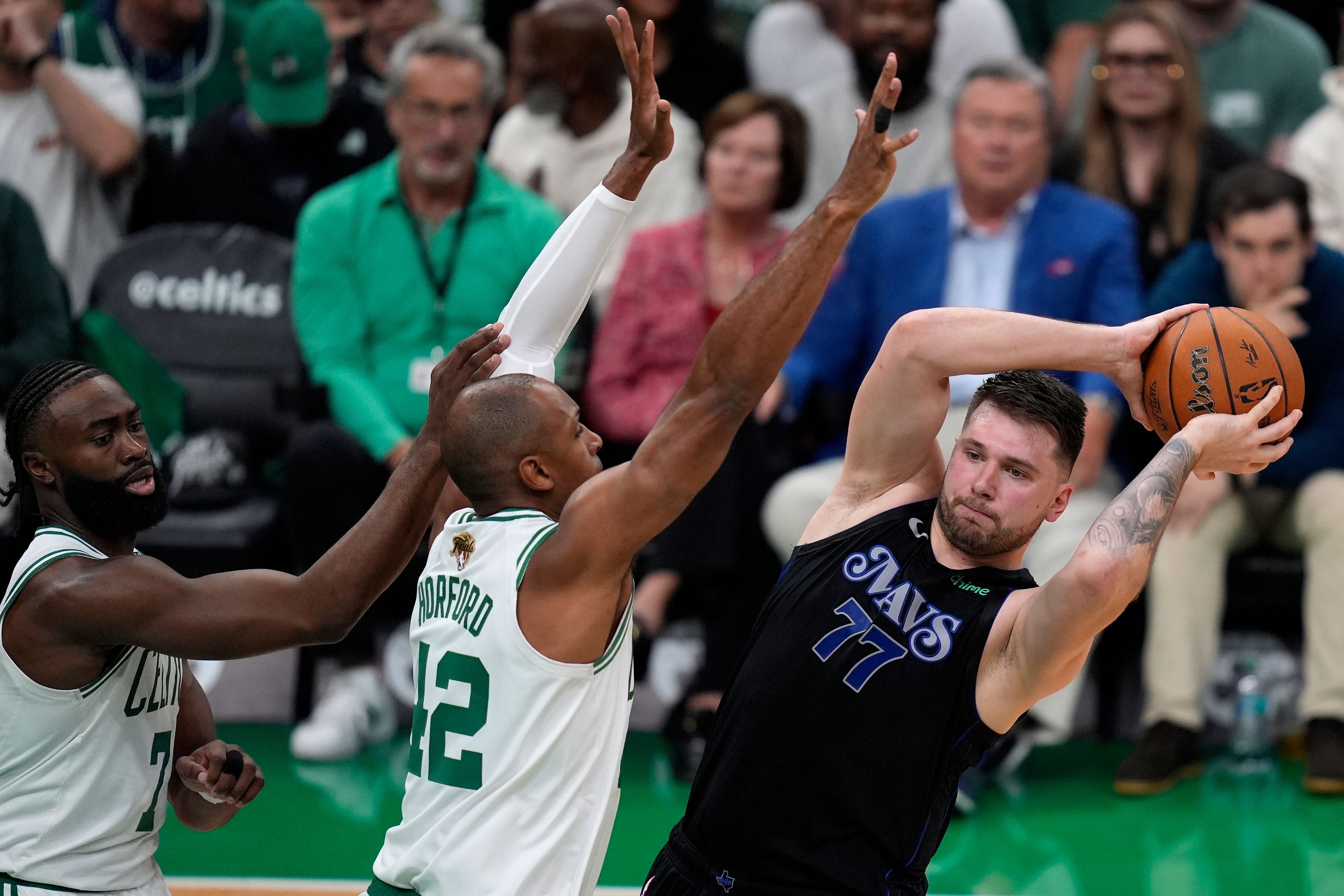 Dallas Mavericks guard Luka Doncic (77) looks for an opening as Boston Celtics guard Jaylen Brown (7) and center Al Horford (42) defend during the first half of Game 1 of basketball's NBA Finals on Thursday, June 6, 2024, in Boston.