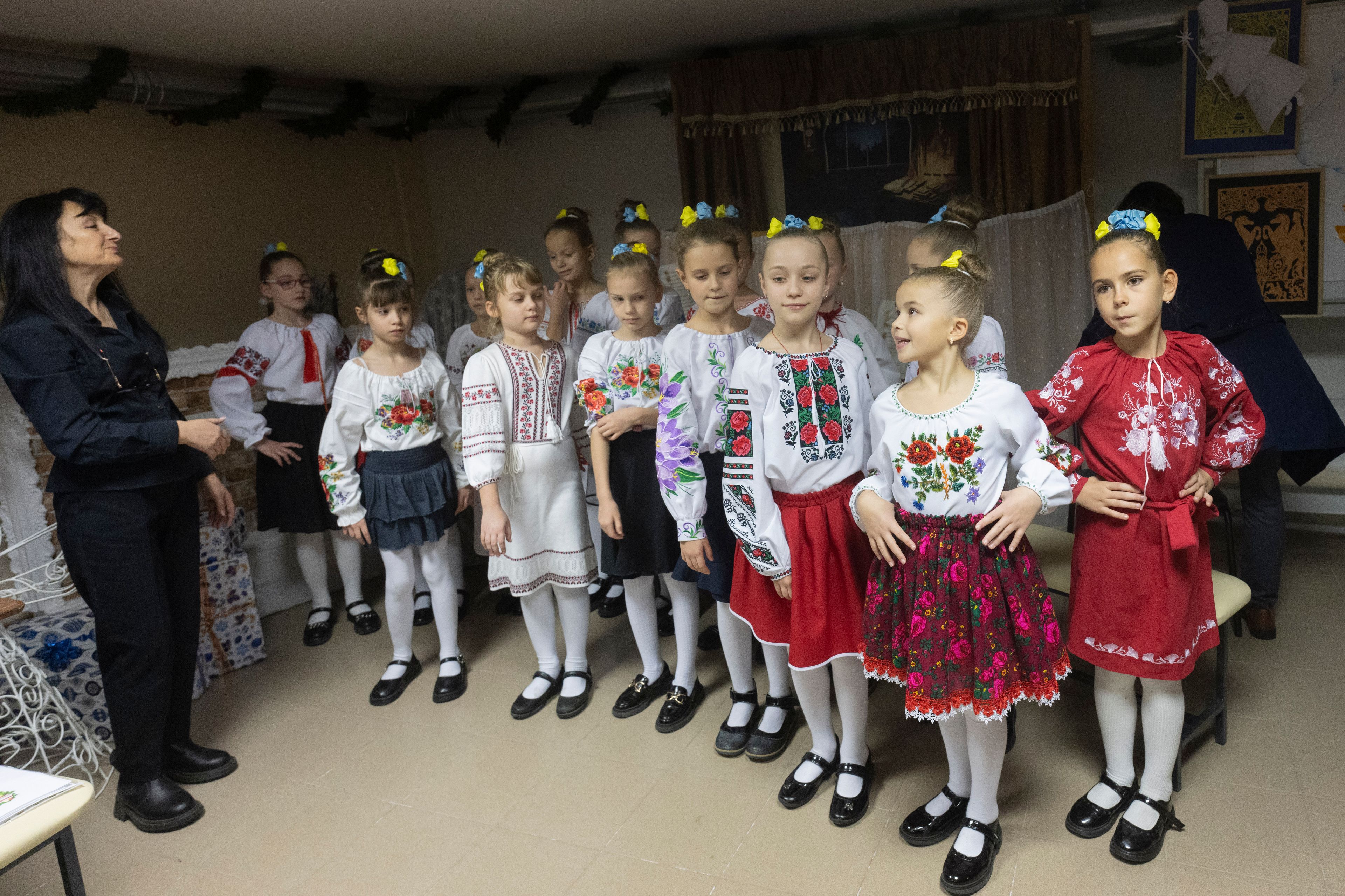 Schoolgirls in national suits perform during opening ceremony for a St. Nicholas Residence and Workshop of Good Deeds in a basement bomb shelter of a military lyceum on World Children's Day in Kyiv, Ukraine, Wednesday, Nov. 20, 2024. (AP Photo/Efrem Lukatsky)