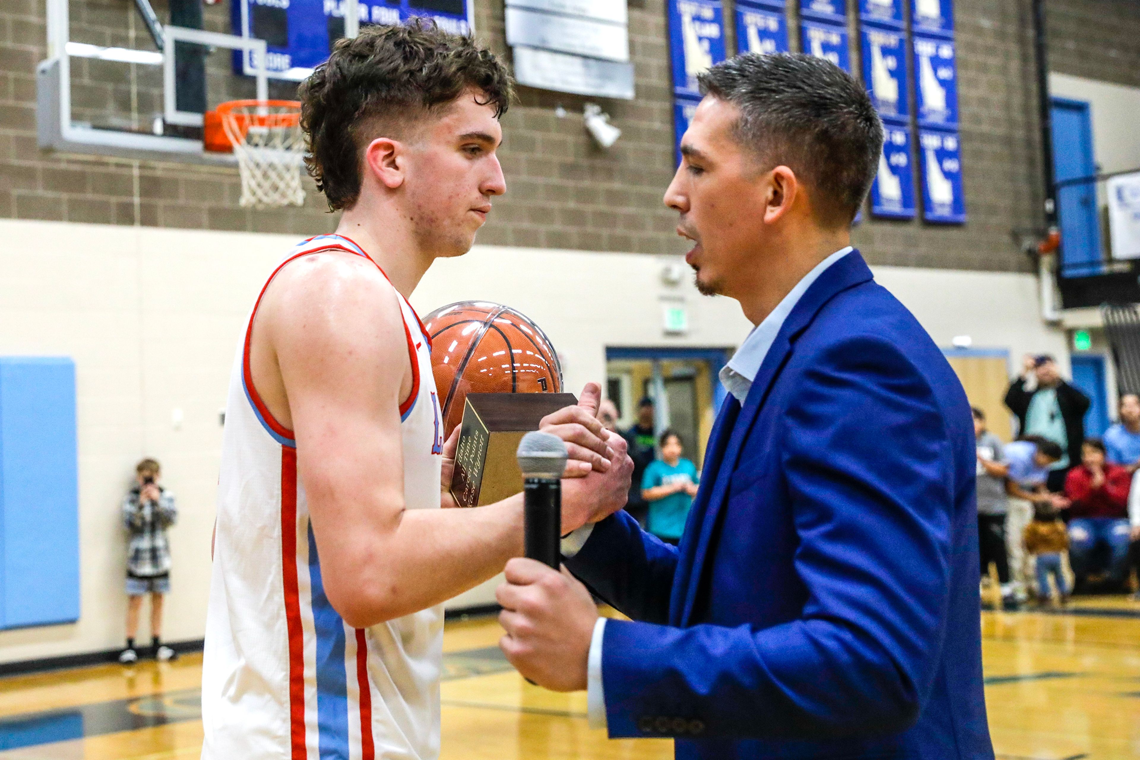 Kase Wynott receives a trophy with the game ball from coach Zach Eastman after breaking the Idaho all-time career points record Jan. 25 at Lapwai.