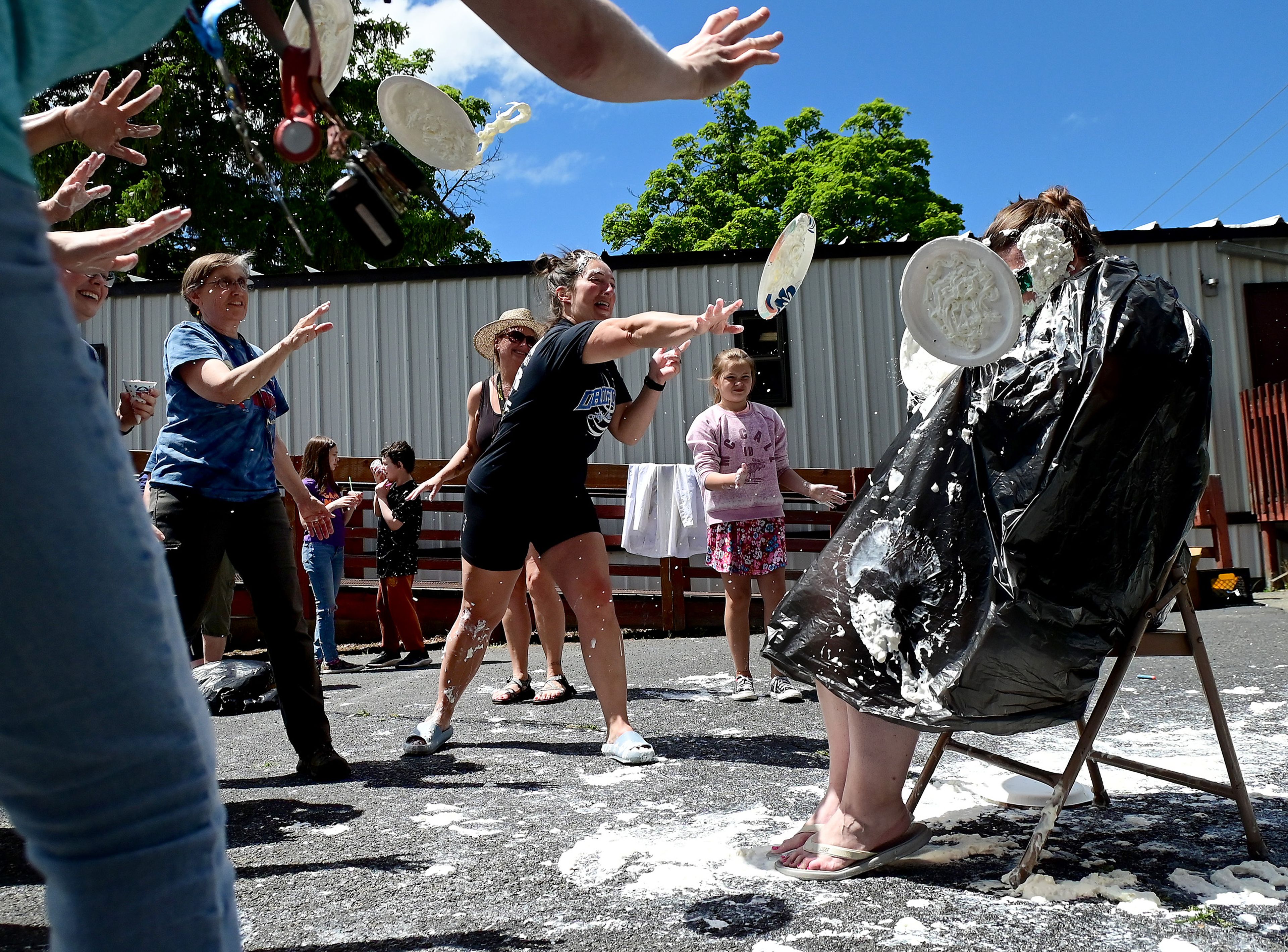 Russell Elementary staff, including Molly Hierschbiel, left, Title1 paraprofessional, Cherisse Lots, back, third grade teacher, and Kayla Anderson, center, building aide, encircle principal Marianne Sletteland, right, to throw whip cream “pies” at Sletteland as part of the end of the school year celebration on the school’s playground on Wednesday.