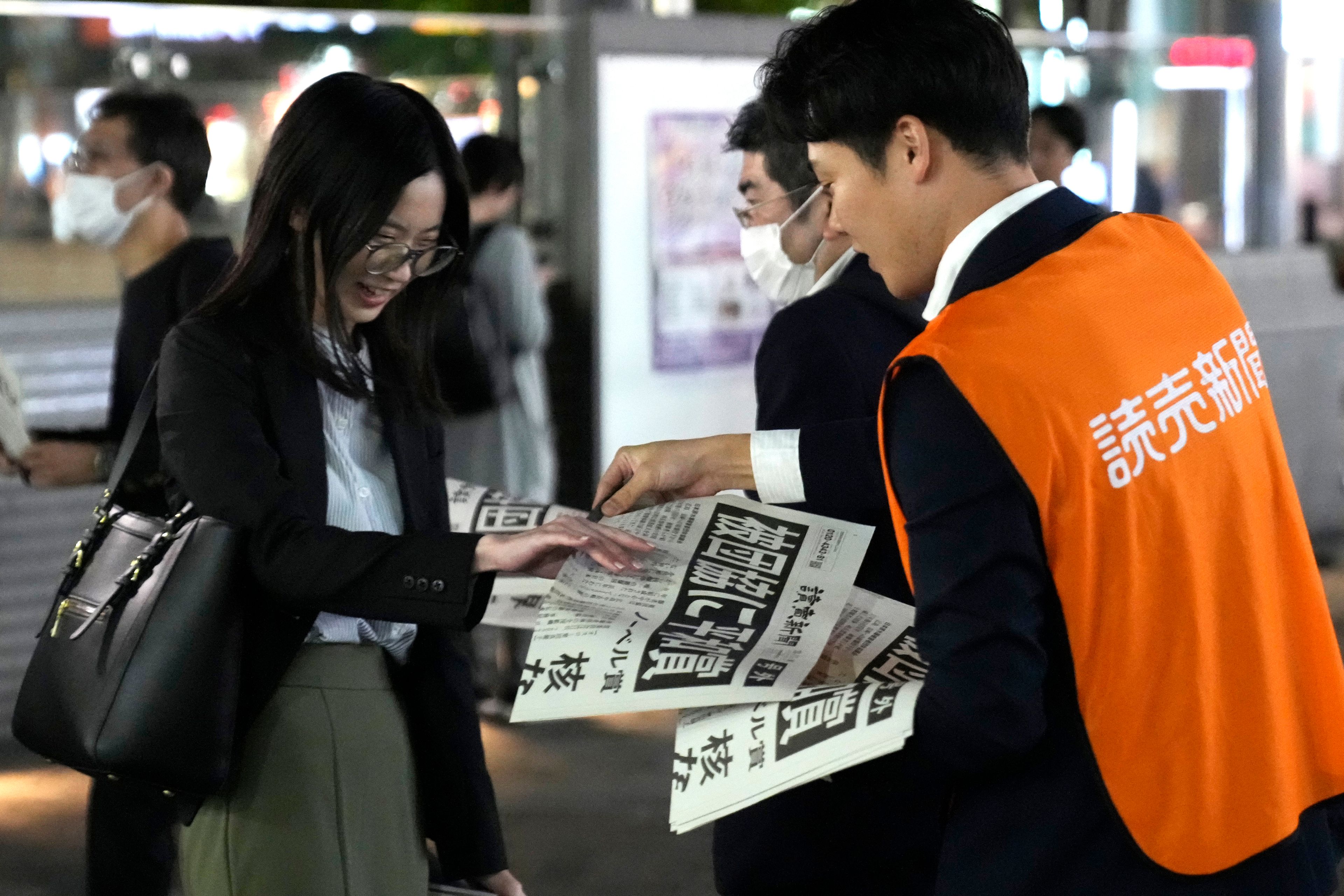 A worker of the Yomiuri Shimbun newspaper hands out copies of an extra version to passersby in Tokyo, Friday, Oct. 11, 2024, after Nihon Hidankyo, or the Japan Confederation of A- and H-Bomb Sufferers Organizations, won the Nobel Peace Prize. (AP Photo/Shuji Kajiyama)