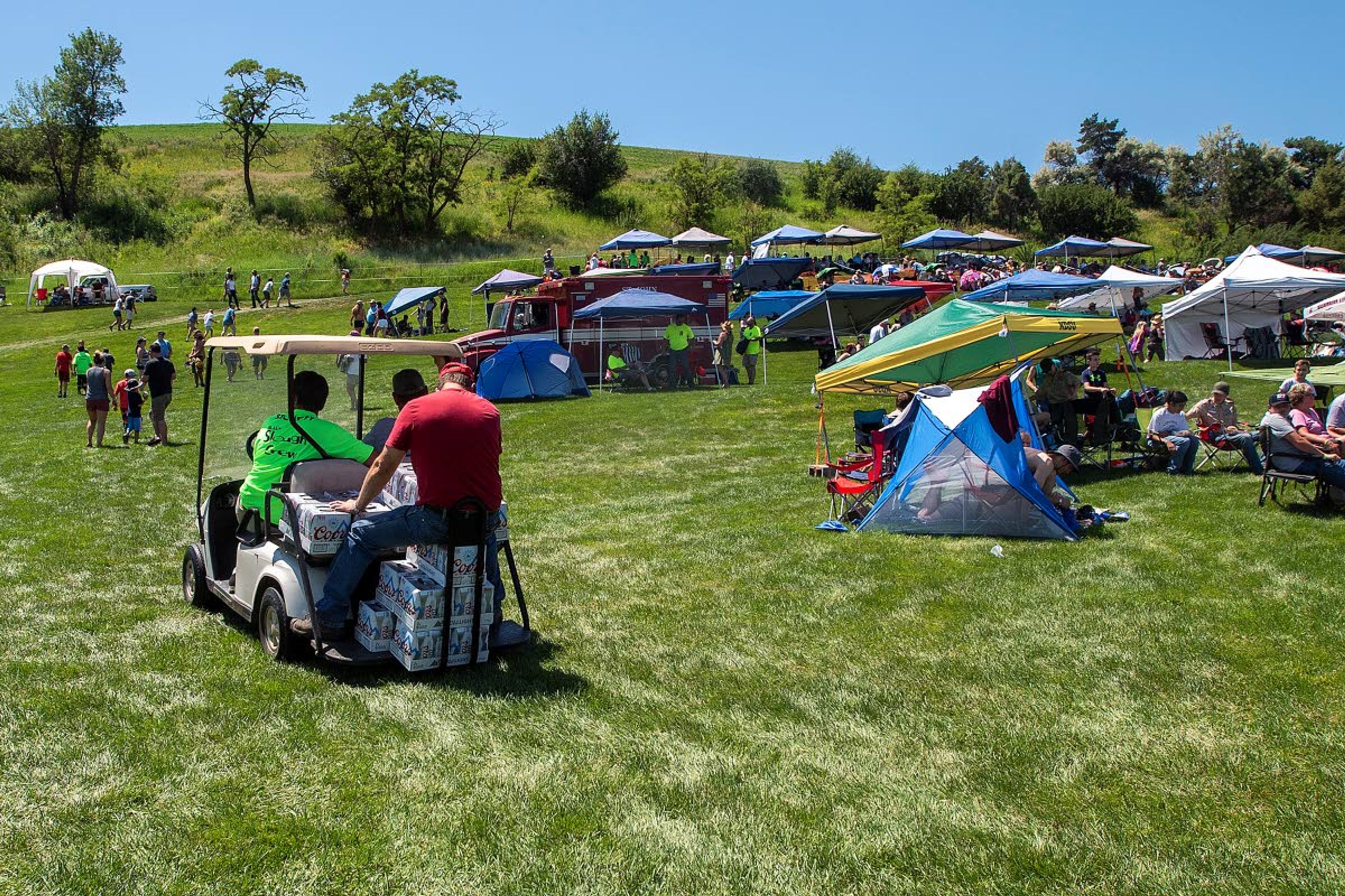 Libations are delivered up to the beer garden atop a hill overlooking Webb's Slough during the sprint boat races on Saturday afternoon in St. John.