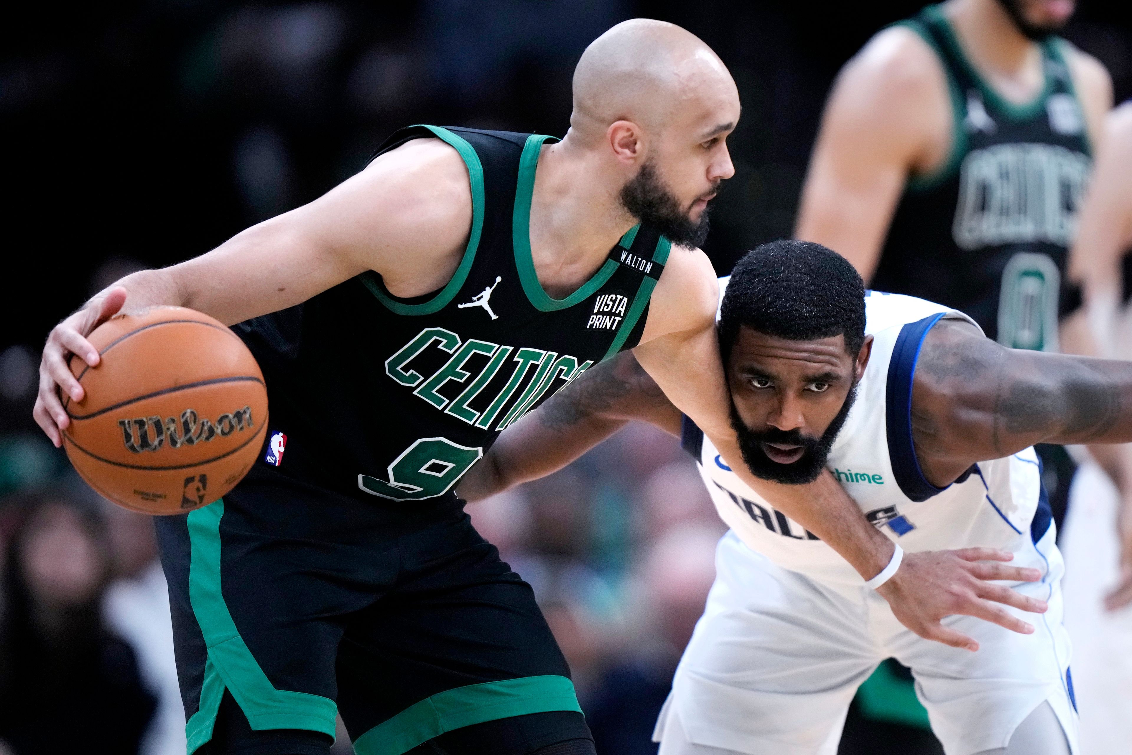 Boston Celtics guard Derrick White (9) holds back Dallas Mavericks guard Kyrie Irving while looking to pass during the second half of Game 2 of the NBA Finals basketball series, Sunday, June 9, 2024, in Boston.