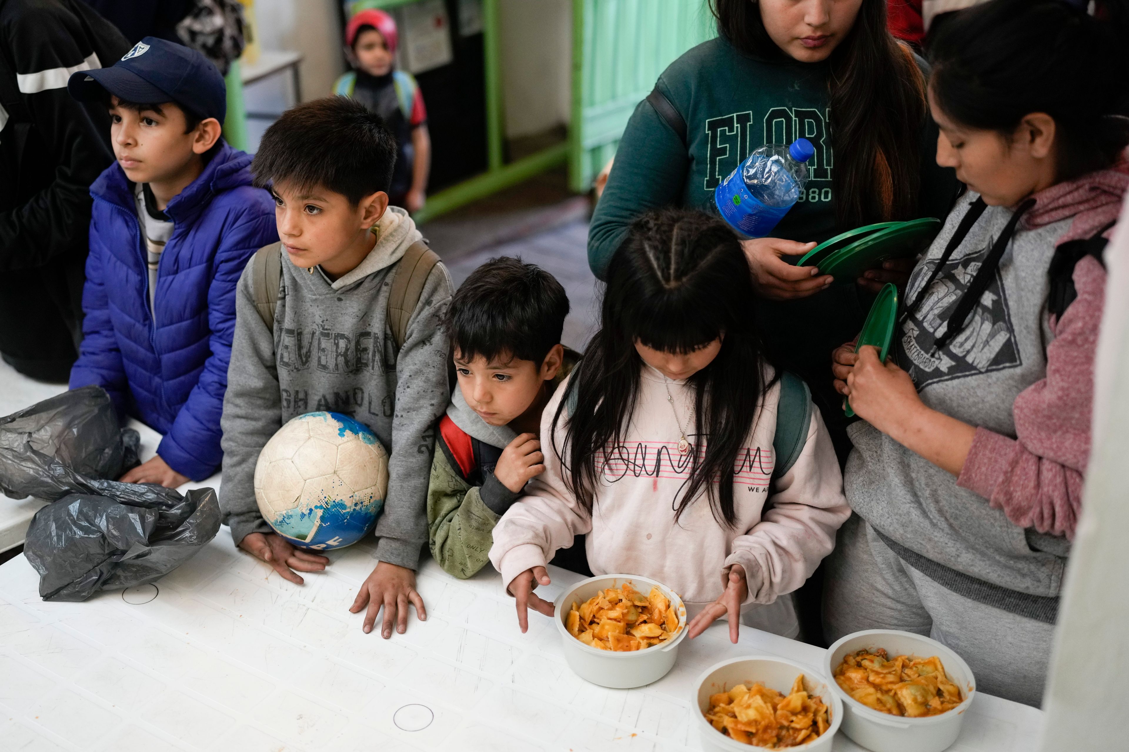 Children wait for a free, cooked meal at a soup kitchen on the outskirts of Buenos Aires, Argentina, Monday, Sept. 9, 2024. (AP Photo/Natacha Pisarenko)