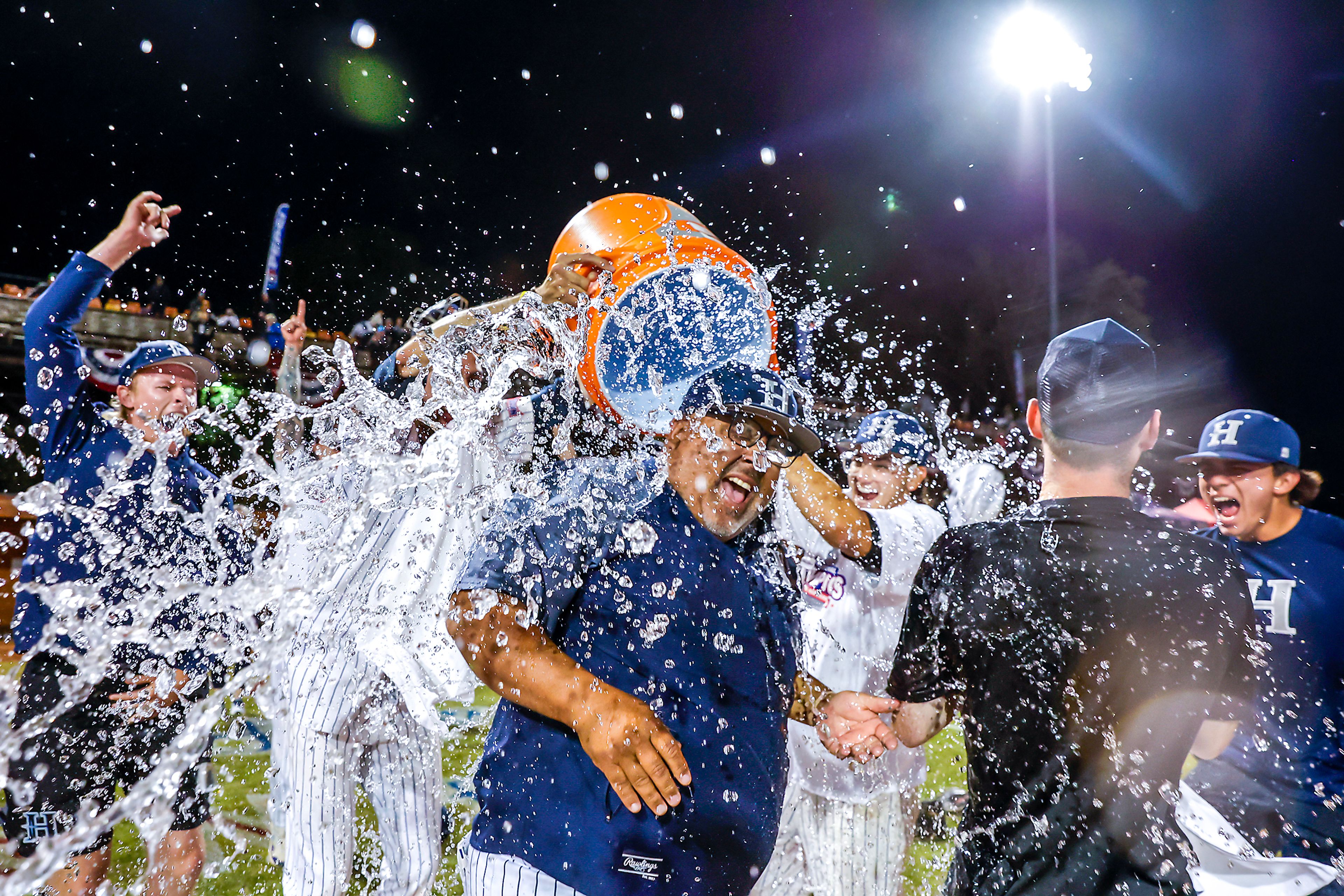 Hope International Head Coach Larry Mahoney gets dowsed by water after they defeated Tennessee Wesleyan 13-6 in Game 19 of the NAIA World Series at Harris Field Friday in Lewiston.